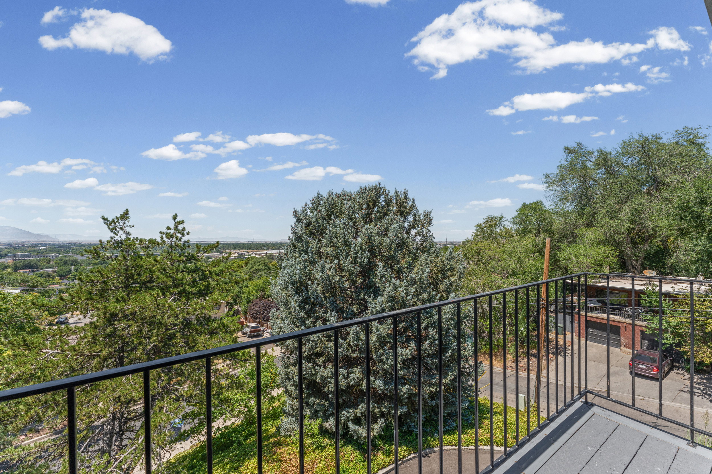 Balcony with black metal railing overlooking a verdant landscape with distant mountains