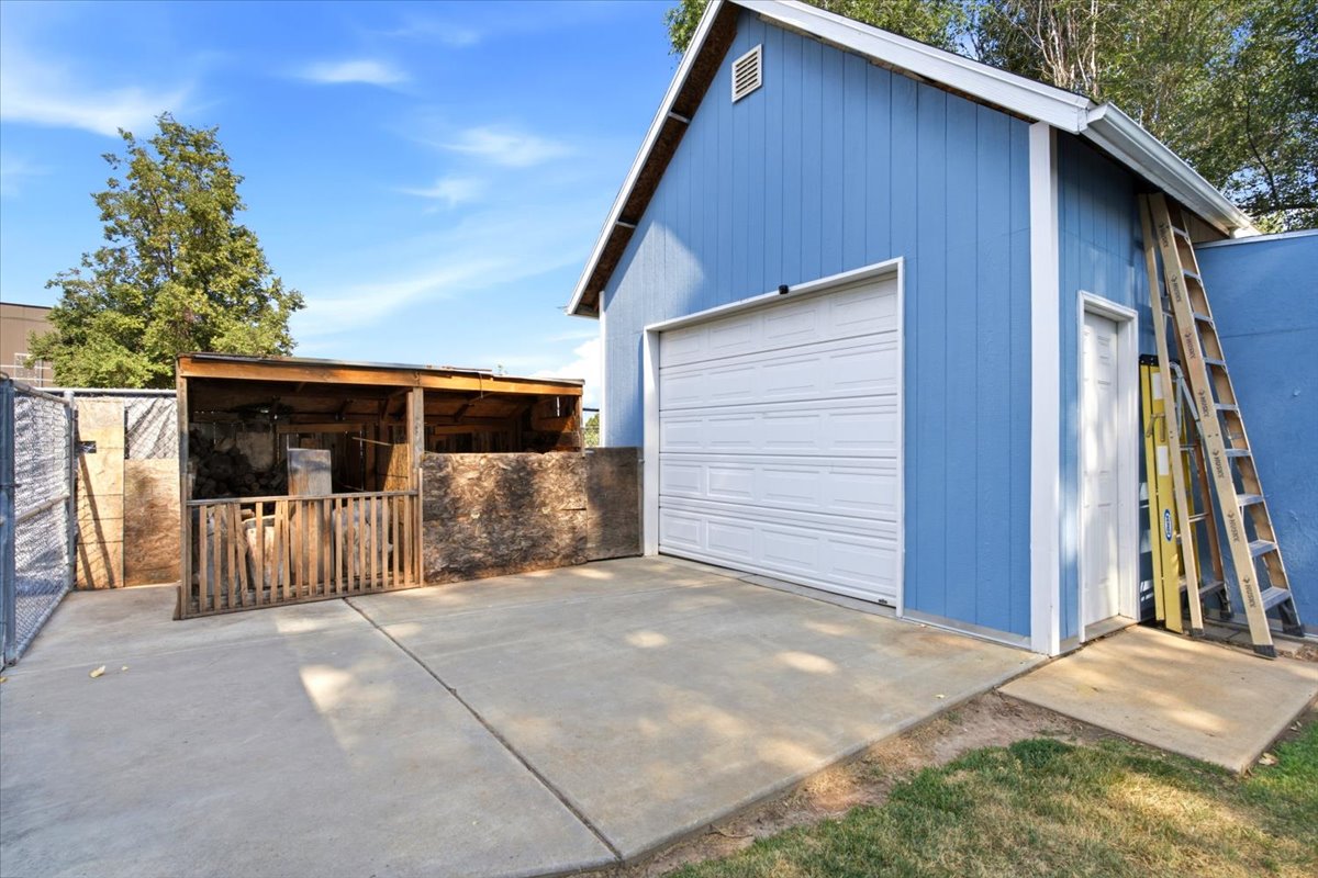 Blue structure featuring a white garage door, a side entry door, and concrete pad