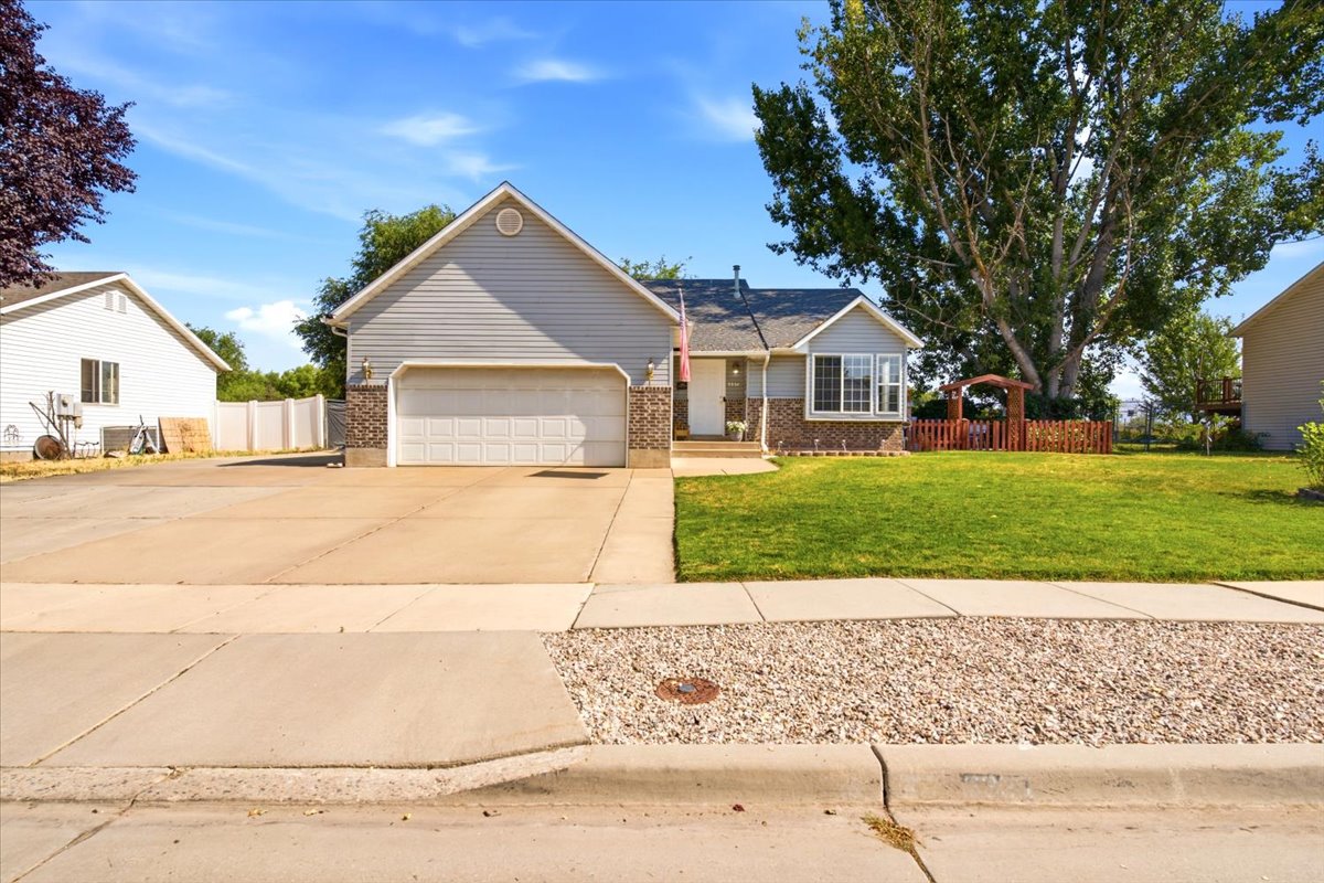 Ranch-style residence featuring a two-car garage, partial brick facade, bay window, and a neatly manicured front lawn