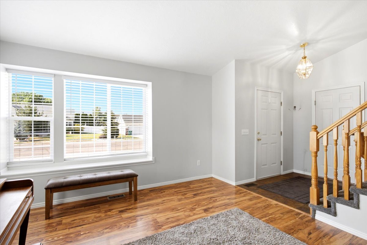 Inviting entryway featuring wood-finish flooring, a contemporary chandelier, and a staircase with a wood handrail