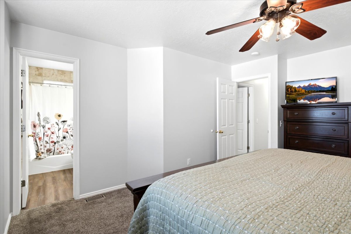 Bedroom featuring neutral wall paint, wood-finish ceiling fan with integrated lighting, and carpet flooring