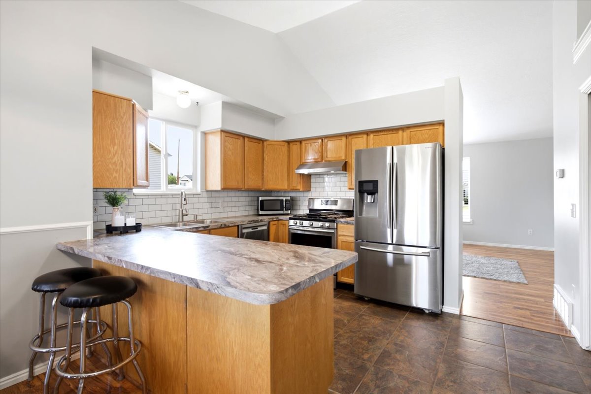 Kitchen with warm-toned cabinetry, stainless steel appliances, and a breakfast bar