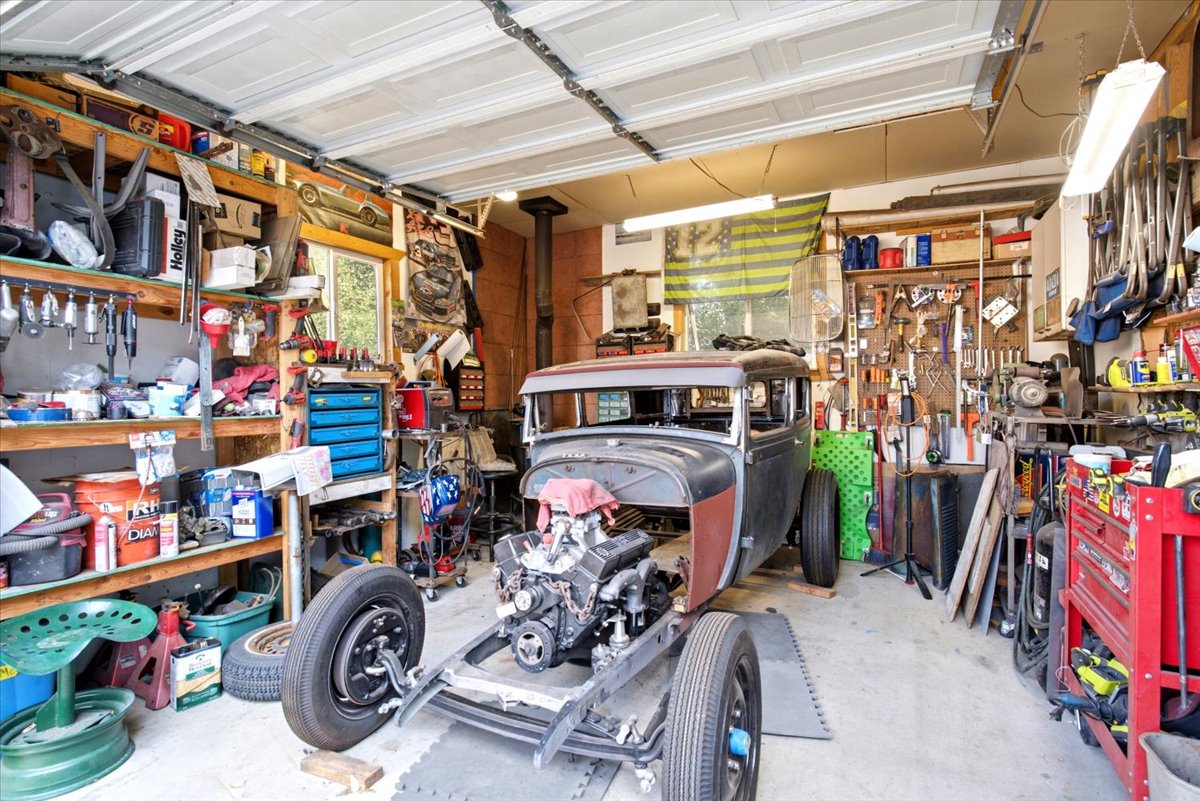 Expansive garage workshop featuring built-in shelving, overhead fluorescent lighting, a window, and a concrete floor