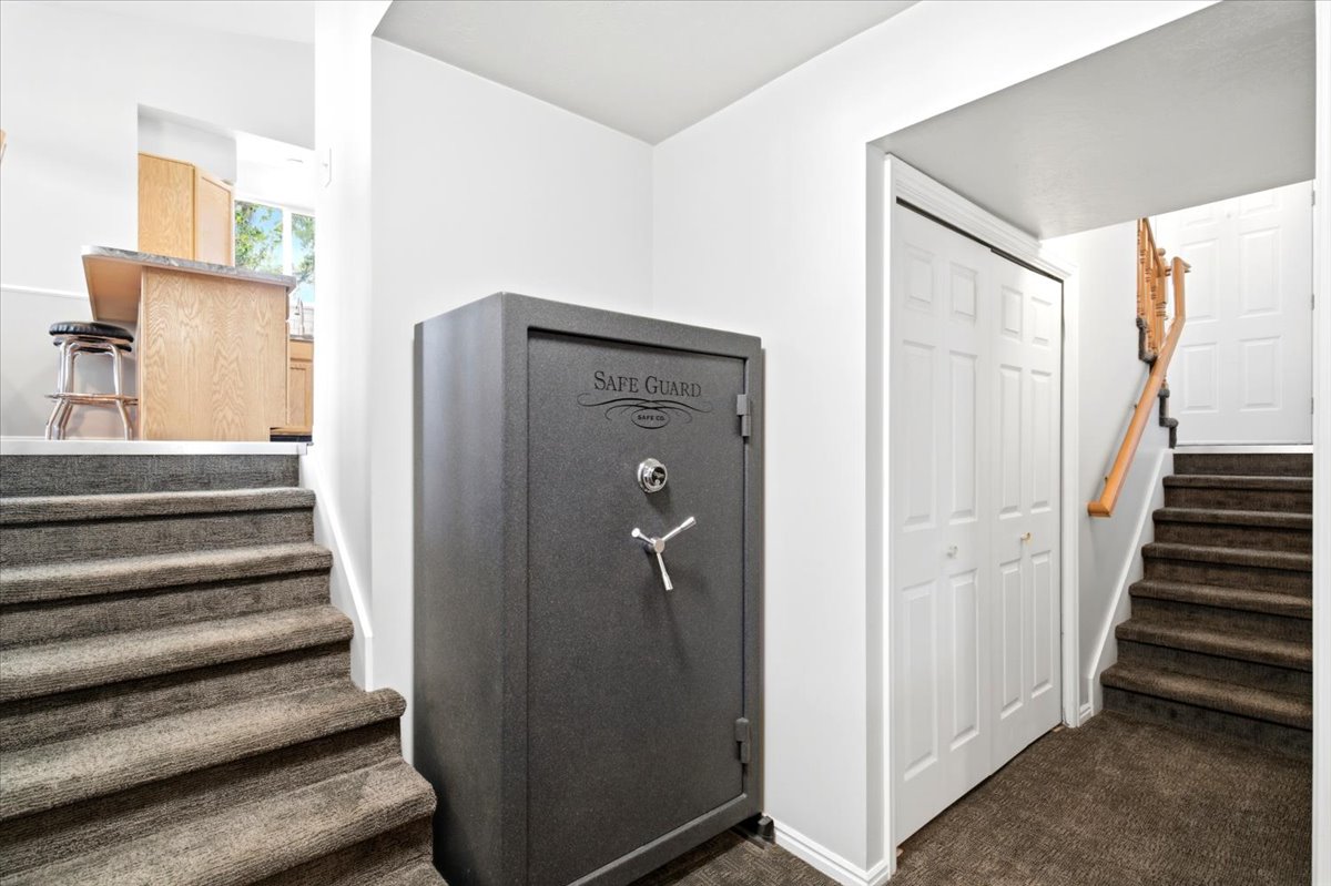 Carpeted staircase featuring a wooden handrail, white paneled bifold doors, and a built-in safe