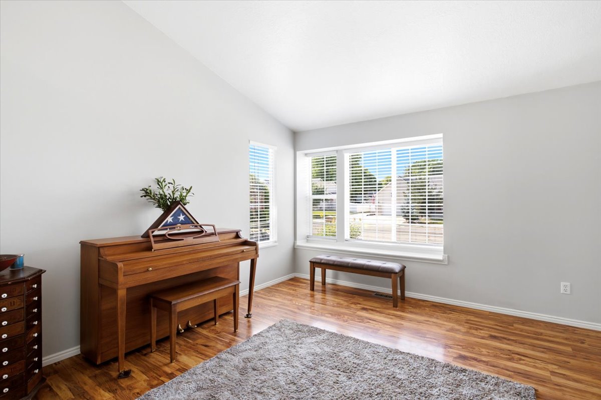 Vaulted ceiling over a room featuring wood-finish flooring and light gray walls