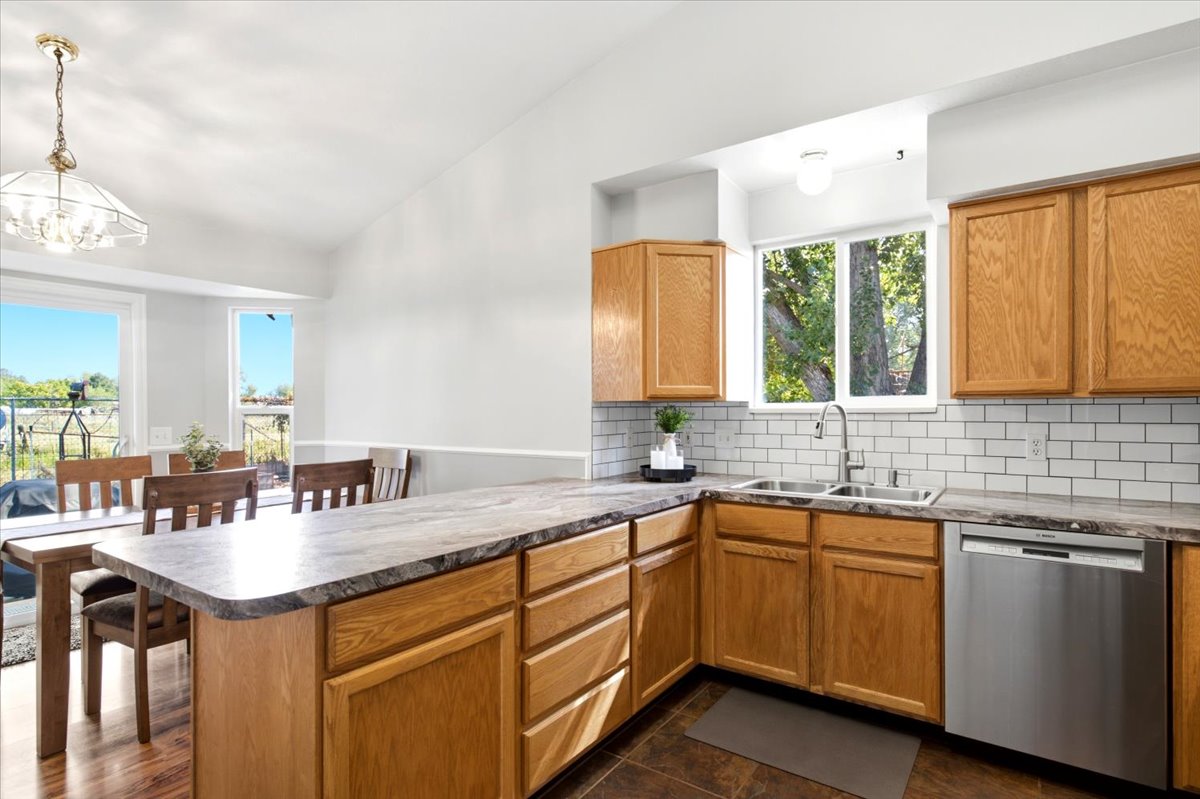 Kitchen featuring wood cabinetry, stainless steel dishwasher, dual basin sink, and subway tile backsplash