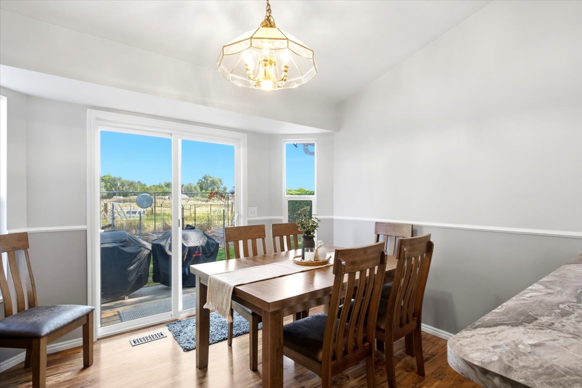Dining area featuring wood-finish flooring, two-tone wall paint with wainscoting, and a decorative ceiling light fixture