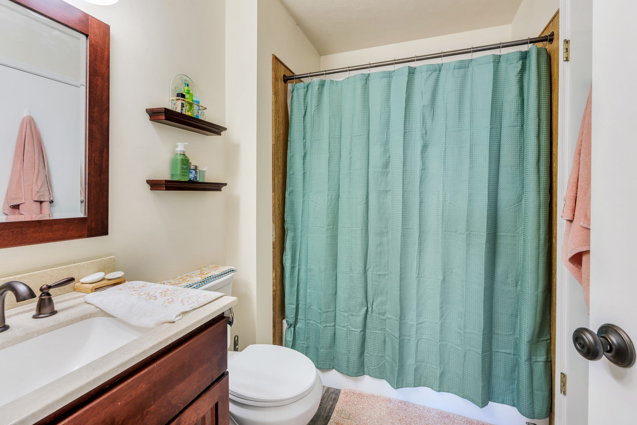 Bathroom featuring a dark wood vanity with a light-toned countertop, an undermount sink, and a bronze-finish faucet