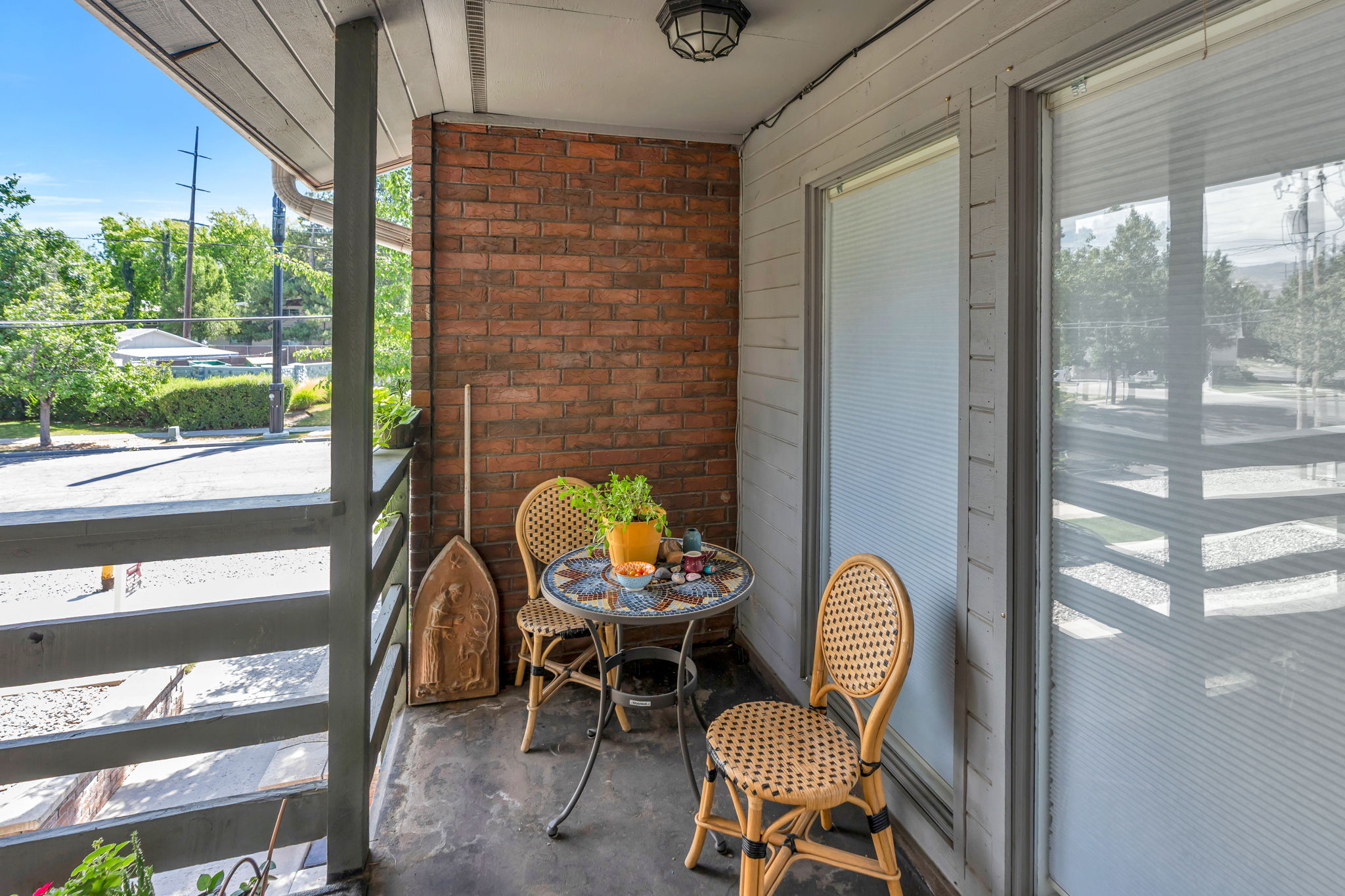 Private outdoor balcony featuring brick and horizontal siding, with a concrete floor and a metal railing