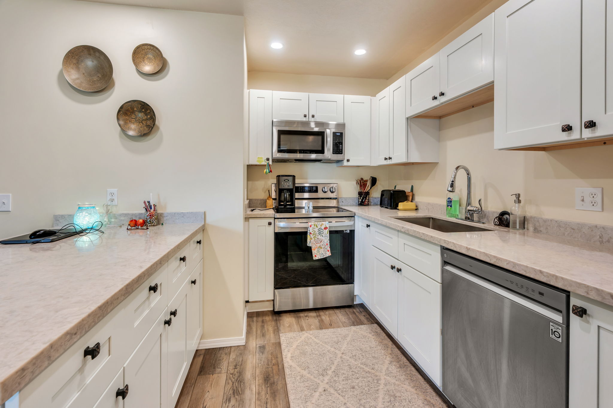 Kitchen featuring white shaker-style cabinetry, light-toned countertops, and wood-finish flooring