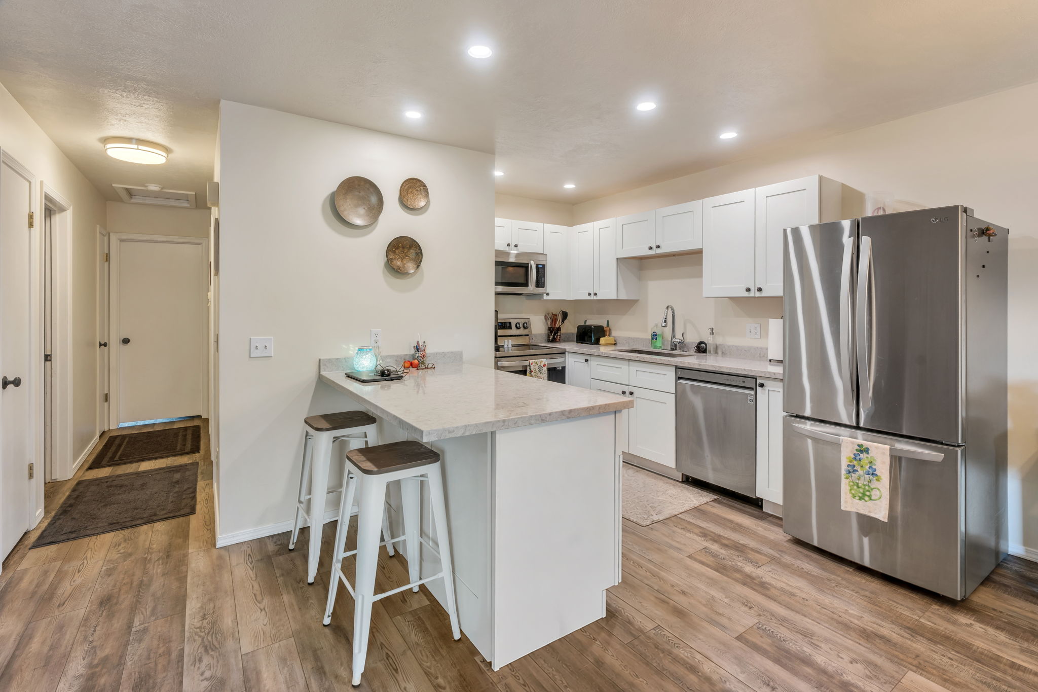 Kitchen featuring light wood-finish flooring, white cabinetry with dark hardware, stainless steel appliances, and light-toned countertops