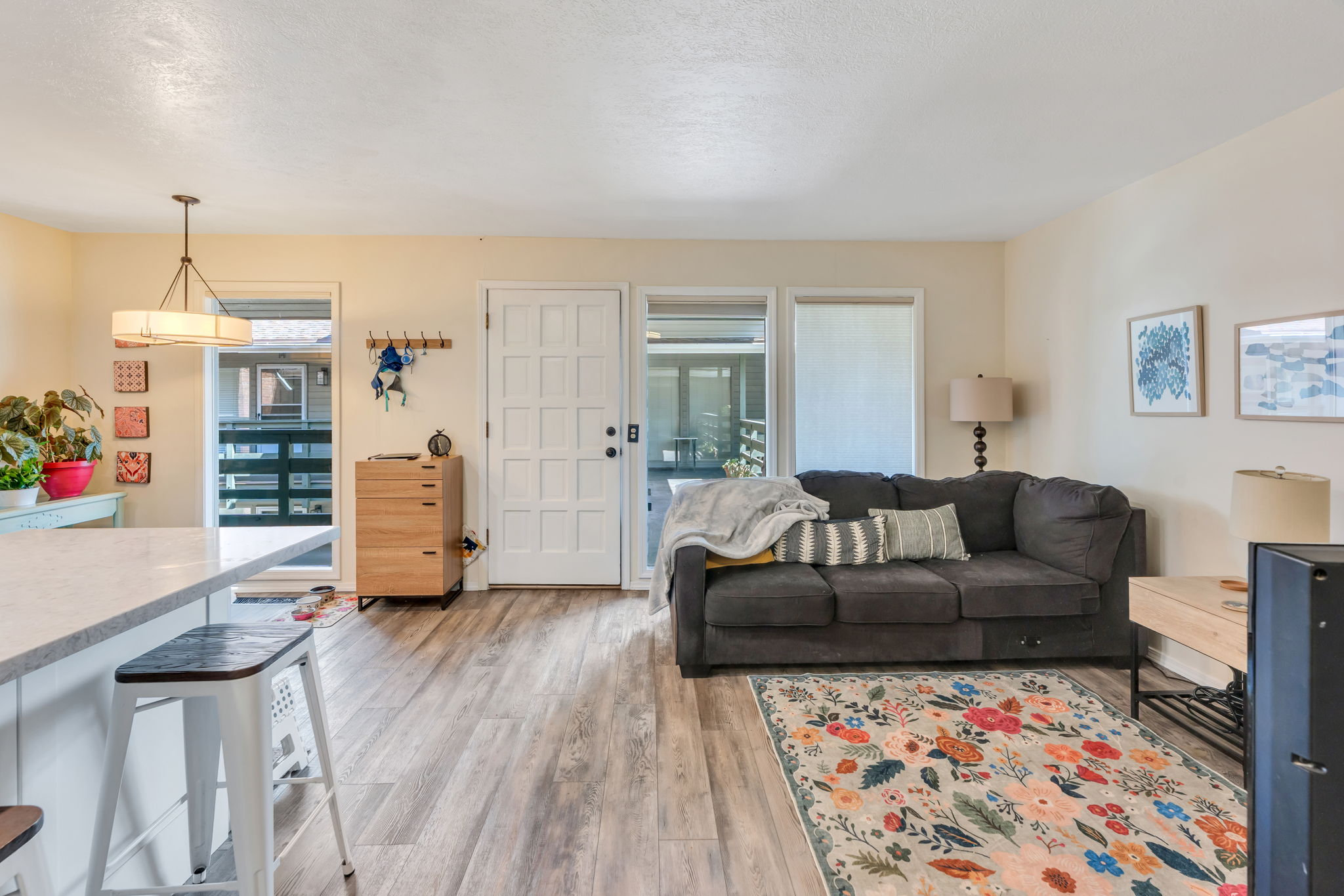 Open concept living area featuring wood-finish flooring, a contemporary ceiling fixture, and a paneled entry door