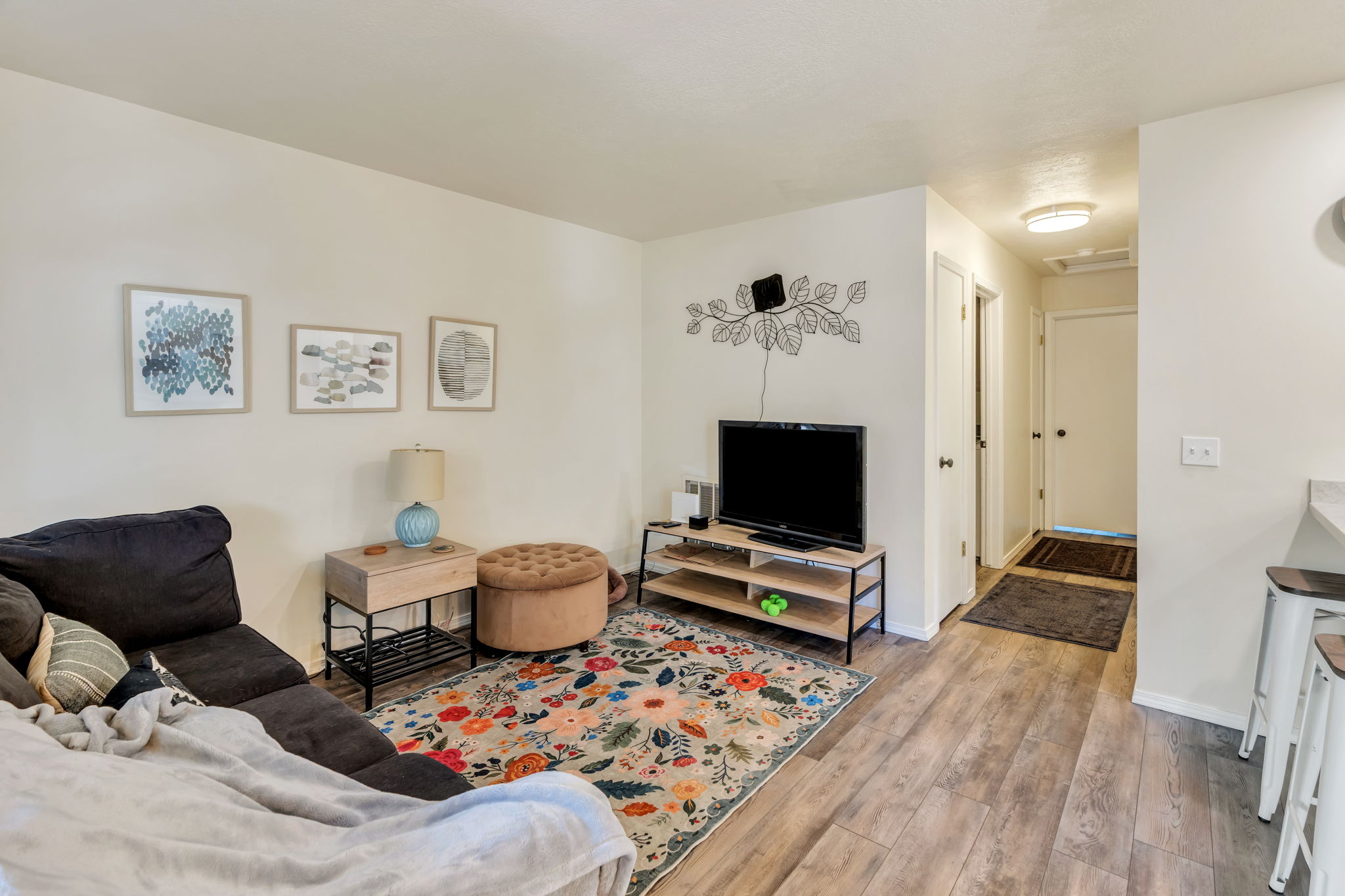Open living area featuring wood-finish flooring, light neutral wall tones, a built-in media console, and an overhead flush-mount light fixture