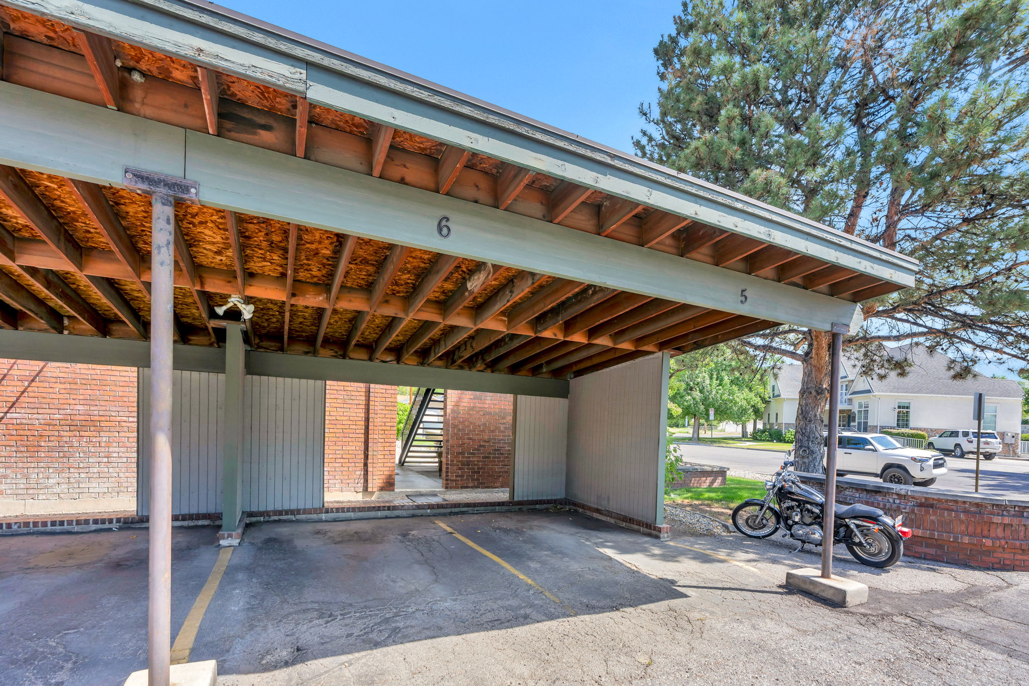 Covered parking structure with numbered spaces, featuring a wood underside and a light green trim