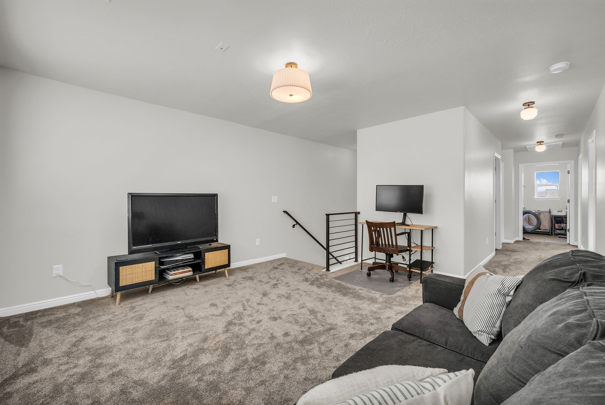 Carpeted recreation room with neutral paint, a contemporary flush mount light fixture, and an open railing staircase