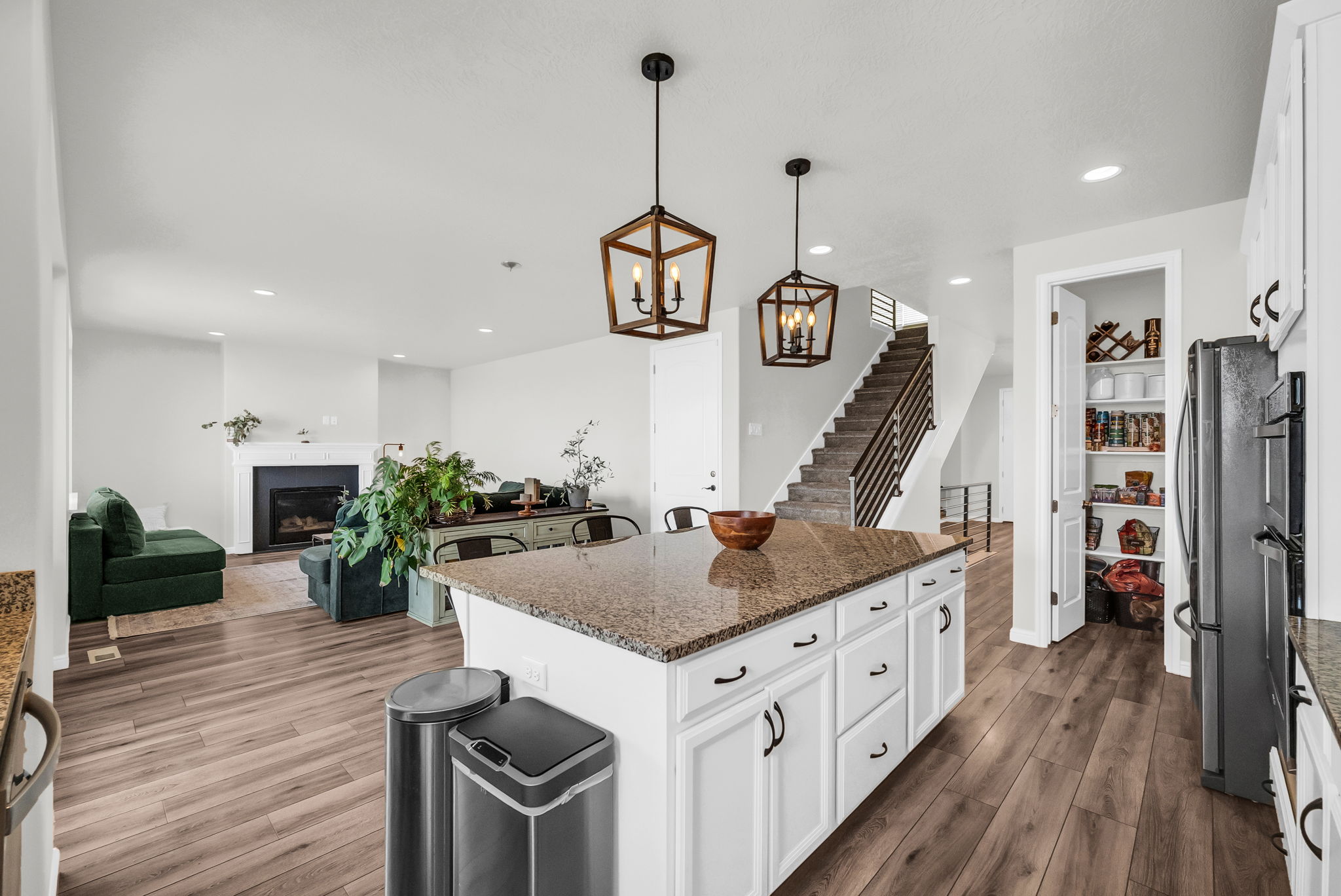 Kitchen island featuring a granite countertop, white cabinetry with dark hardware, and two pendant light fixtures