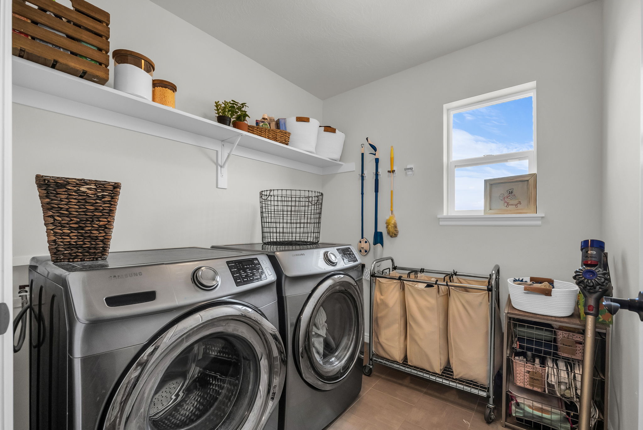 Dedicated laundry area featuring a single window, two wall-mounted shelves, and light-toned wall paint