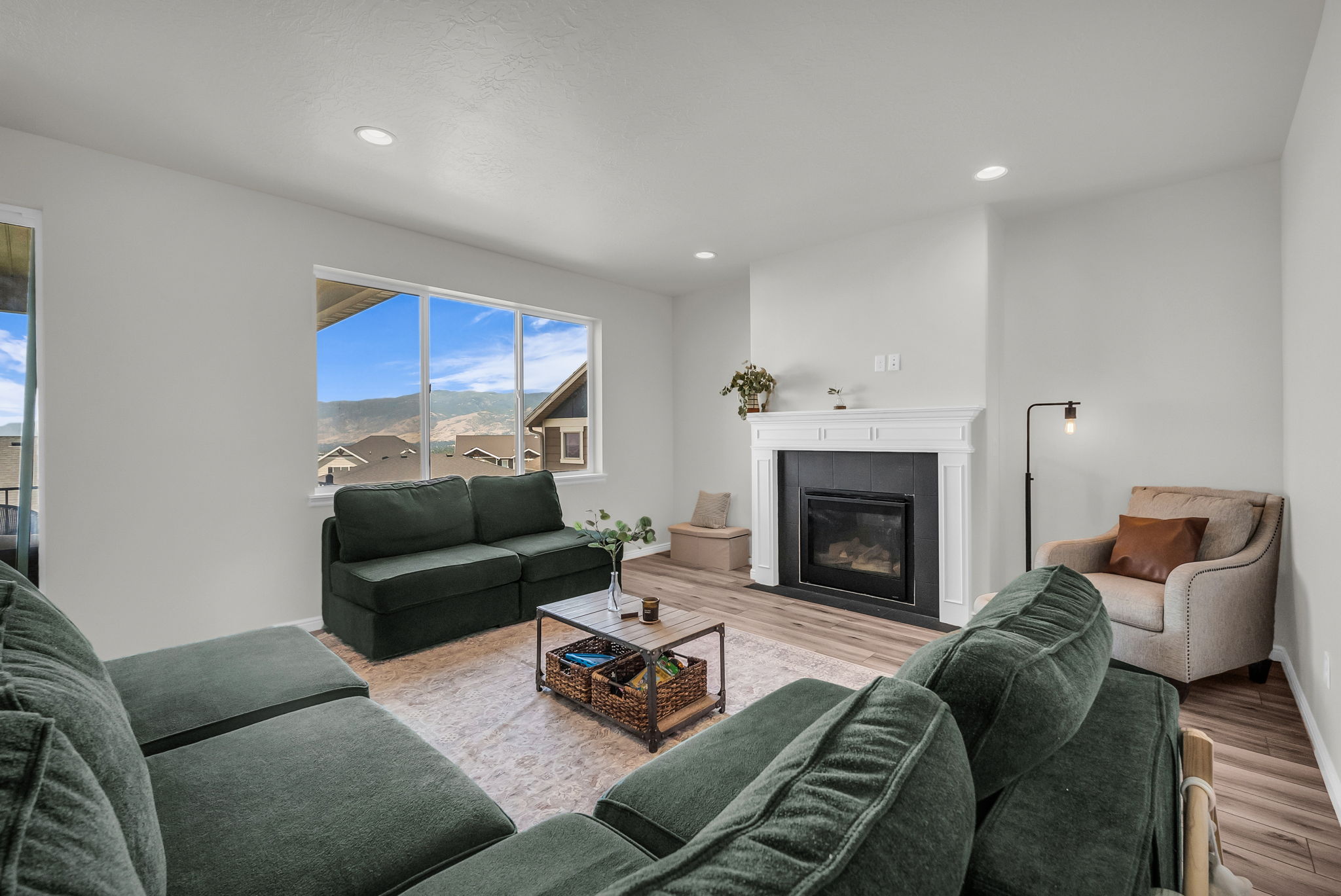Spacious living area featuring large windows, wood-finish flooring, recessed lighting, and a built-in fireplace with a decorative mantel and dark surround