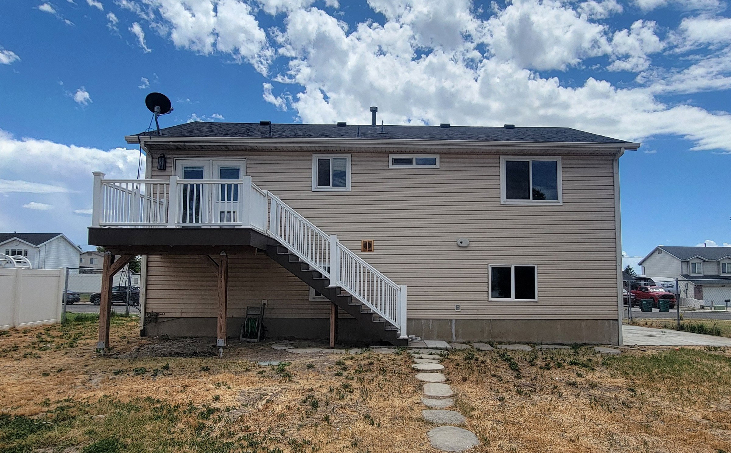 Rear exterior featuring a two-story design with beige horizontal siding, a dark roof, and white-trimmed windows