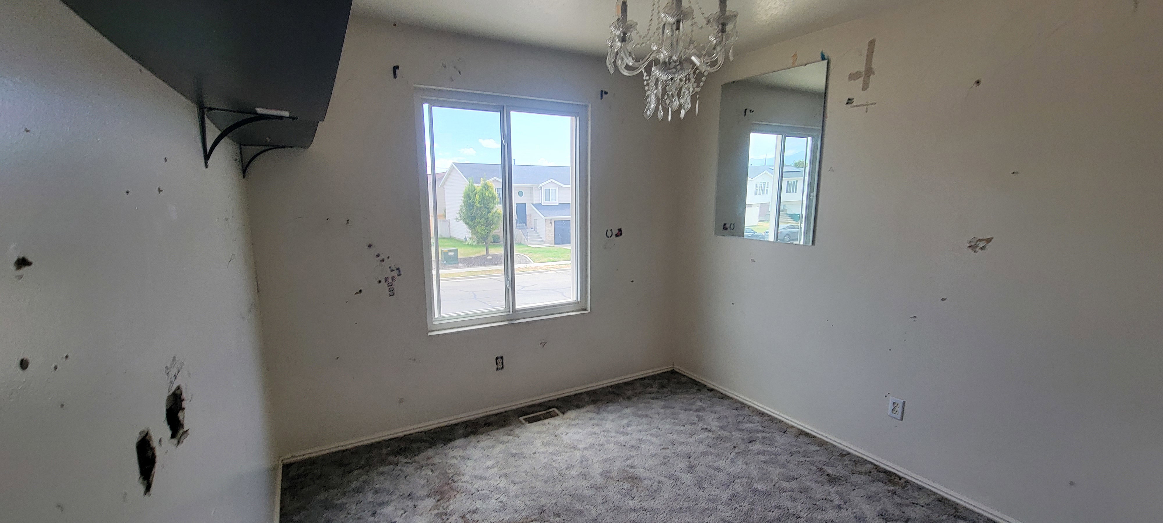 Room featuring a double-pane window, crystal chandelier, and wall-mounted mirror