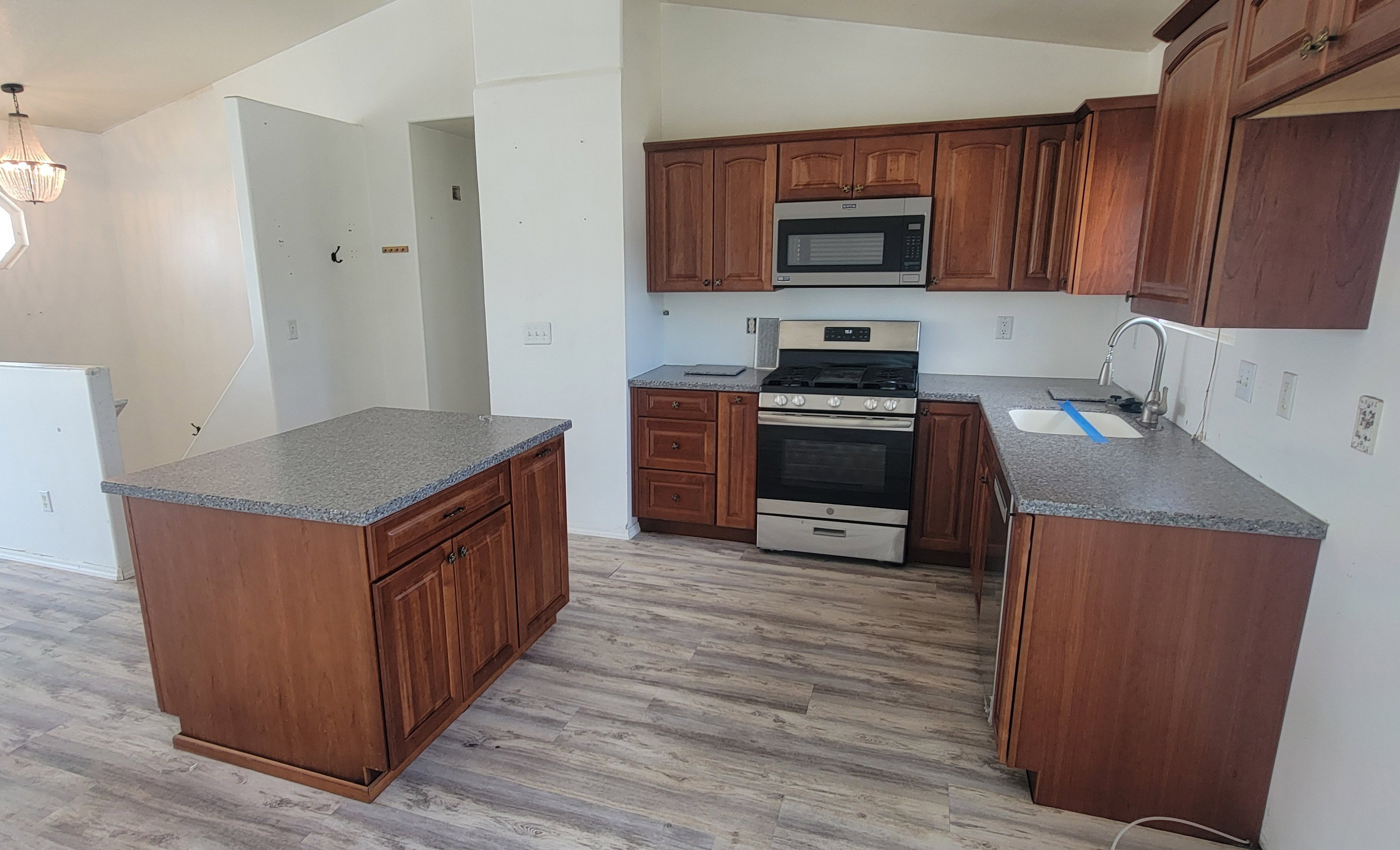 Kitchen featuring wood-finish cabinetry, speckled countertops, and wood-finish flooring
