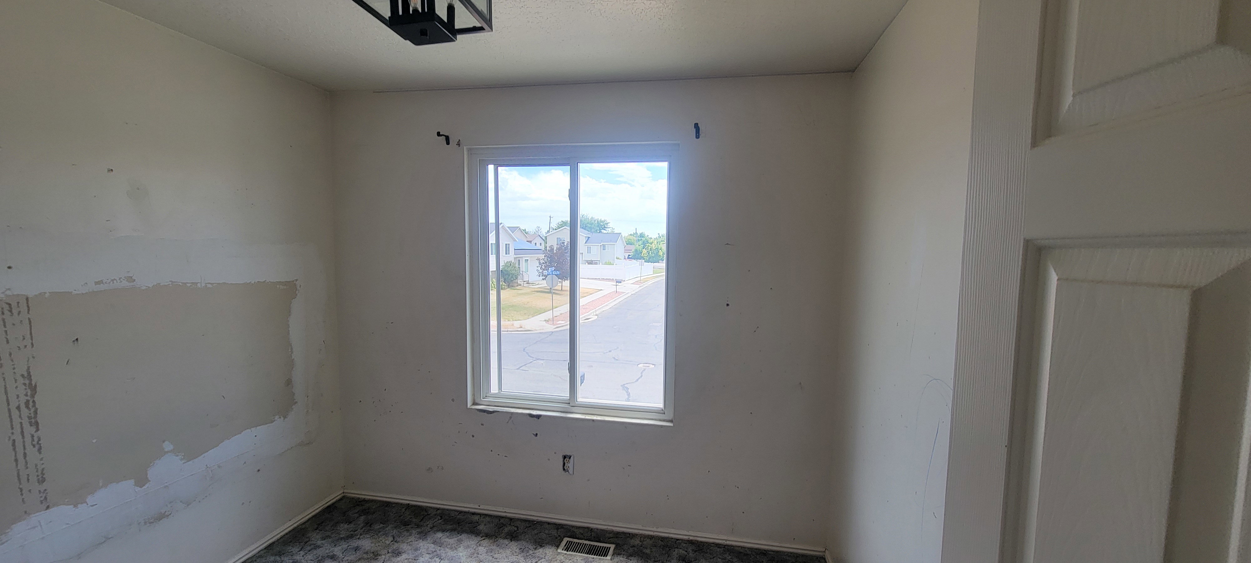 Room featuring a white-framed window, overhead light fixture, white interior door, and wall-to-wall carpeting