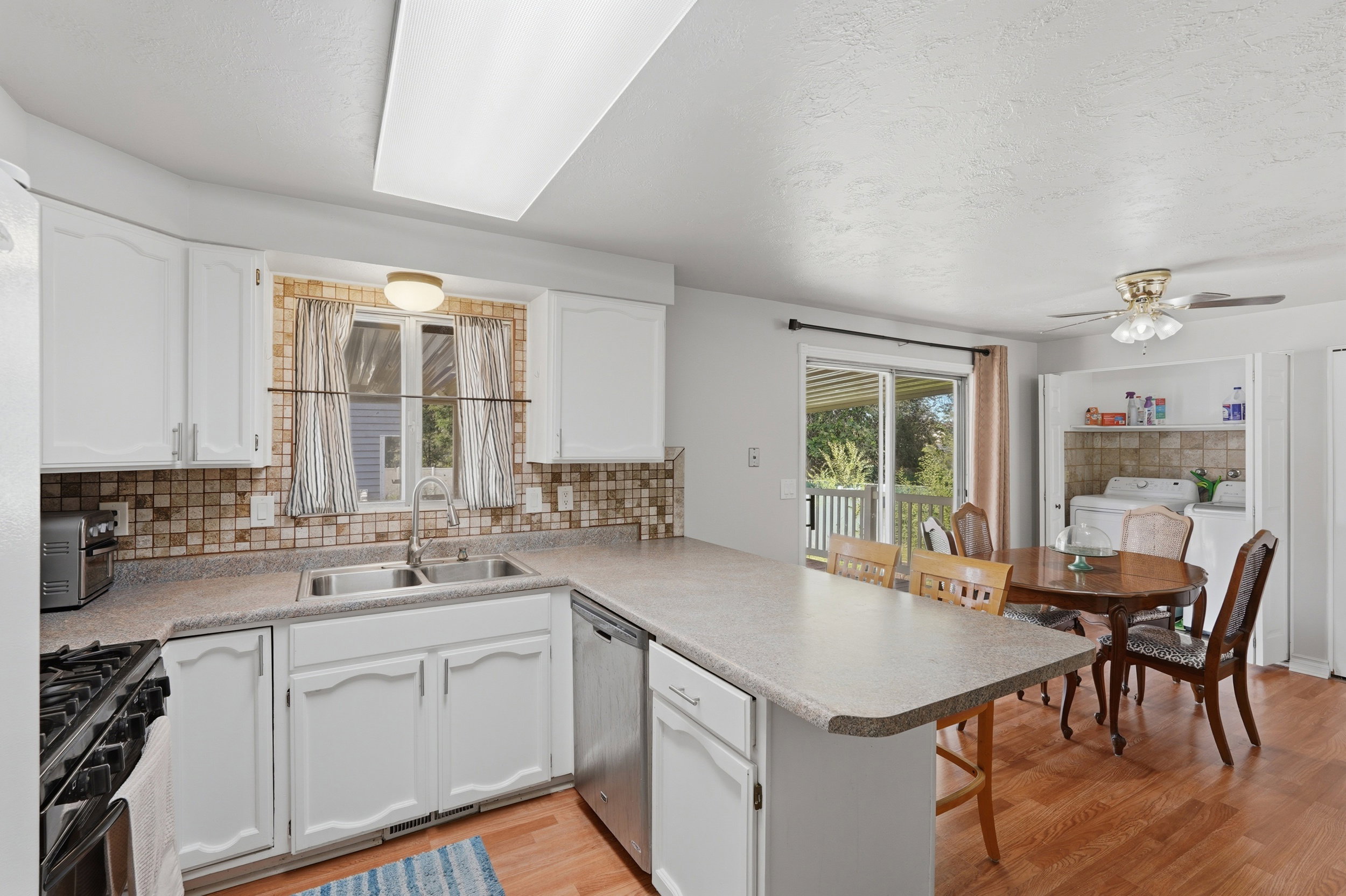 Kitchen featuring white cabinetry, a double basin sink, and a multi-tone tile backsplash
