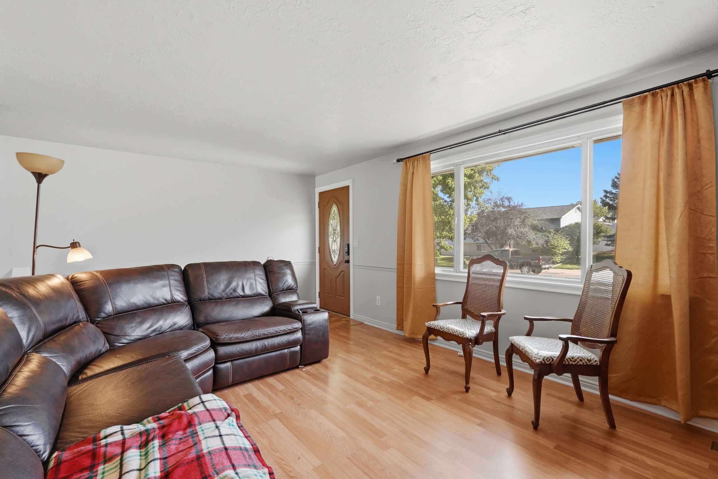 Hardwood-finish flooring throughout, featuring a multi-pane front window and a wooden entry door with an oval glass insert