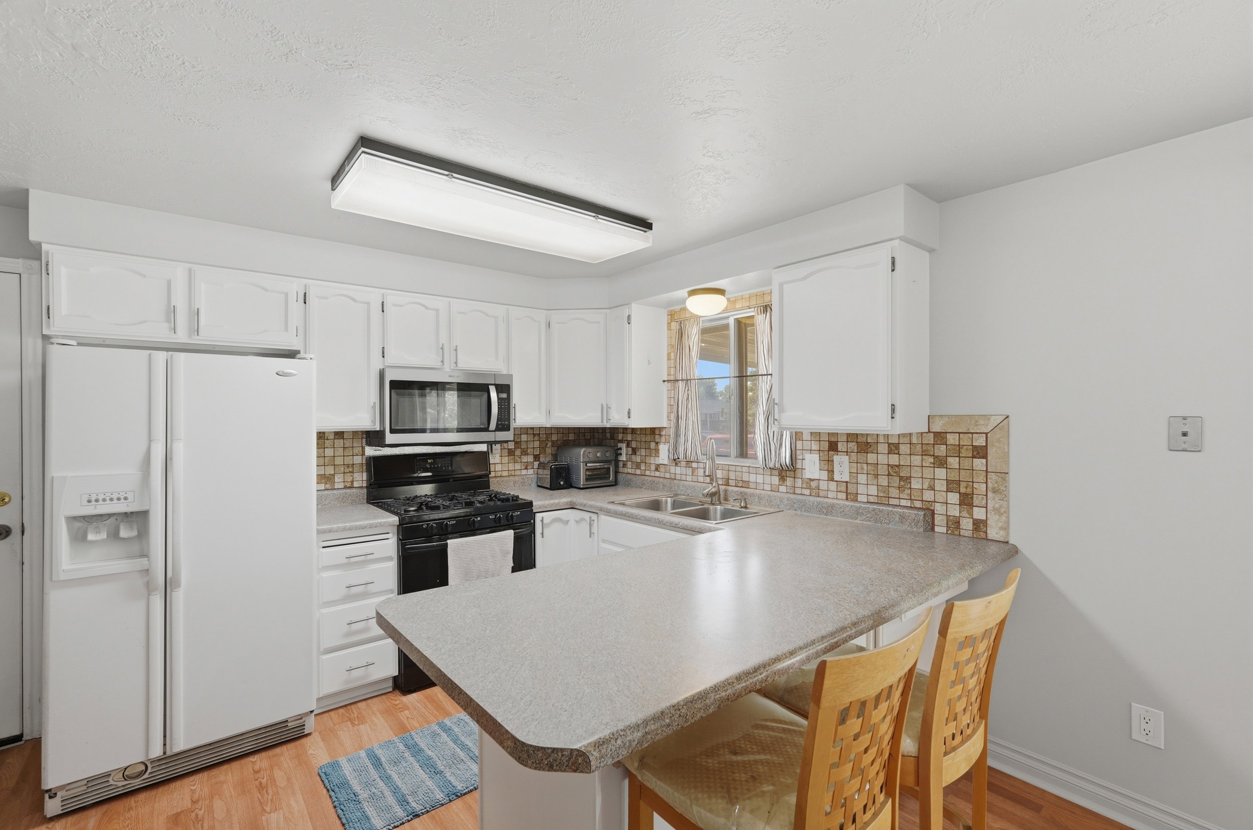 Kitchen featuring white cabinetry, a built-in microwave, a black gas range, and a breakfast bar