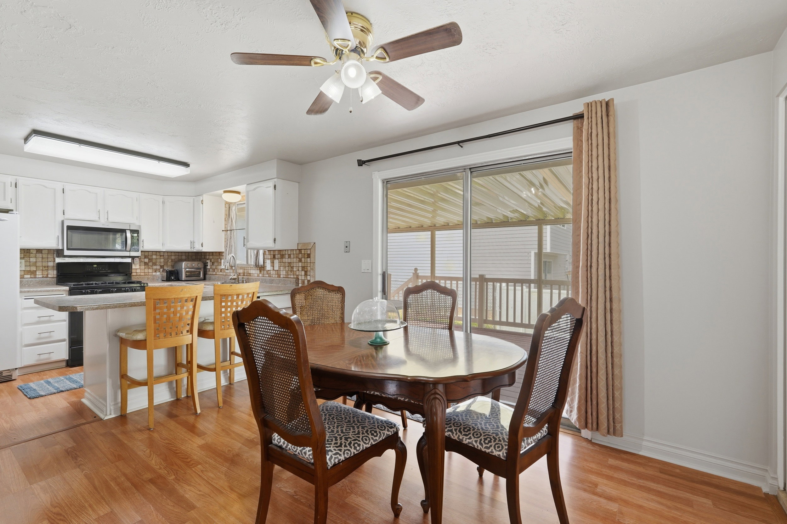 Open-concept kitchen and dining area featuring wood-finish flooring, white cabinetry, and stainless steel appliances