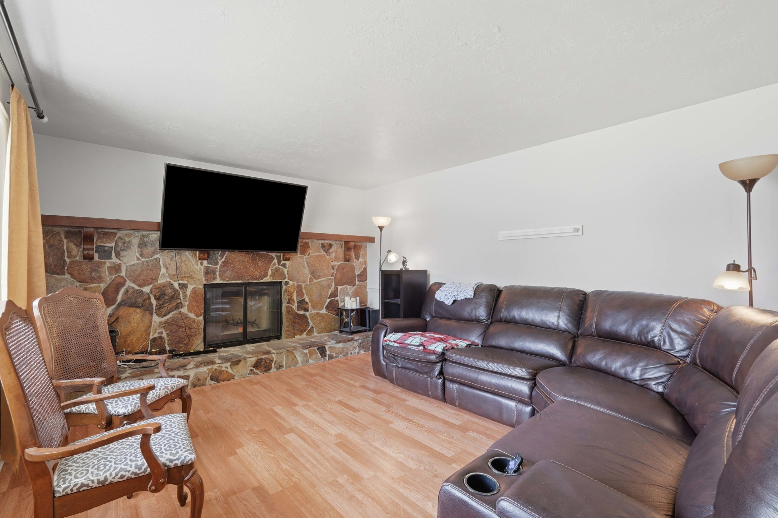 Natural stone fireplace with a wood mantle and hearth, featuring a glass-front firebox