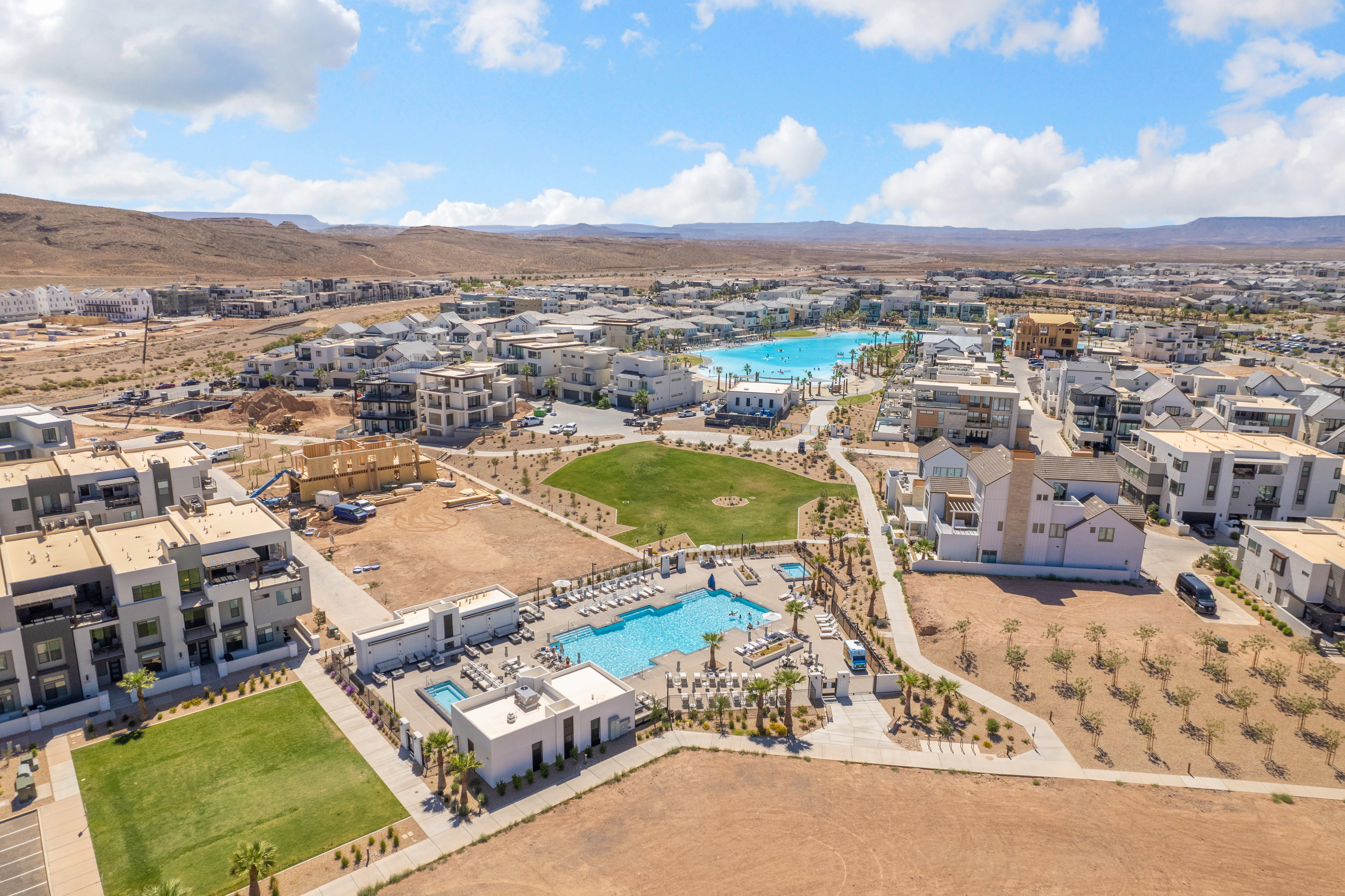 Aerial perspective showcasing a community with numerous residential structures, recreational pool areas, and a large central lagoon