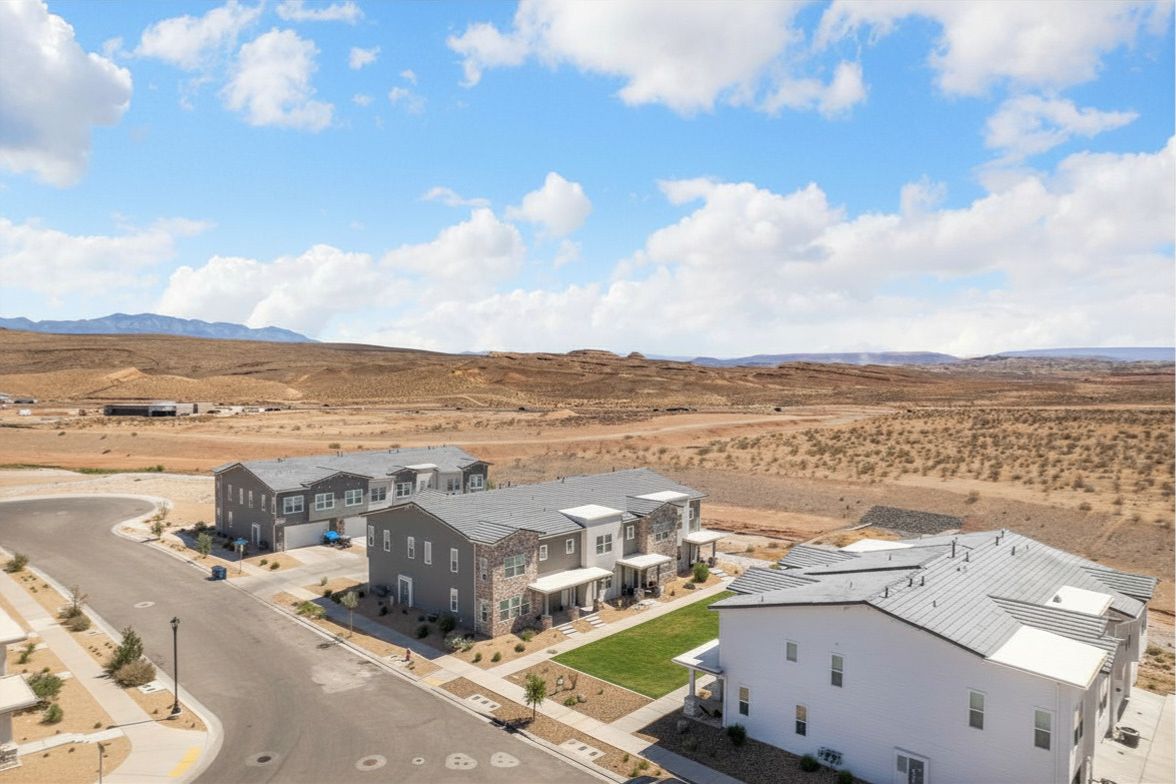 Contemporary residential development featuring a paved street, desert landscaping, and a distant mountain backdrop