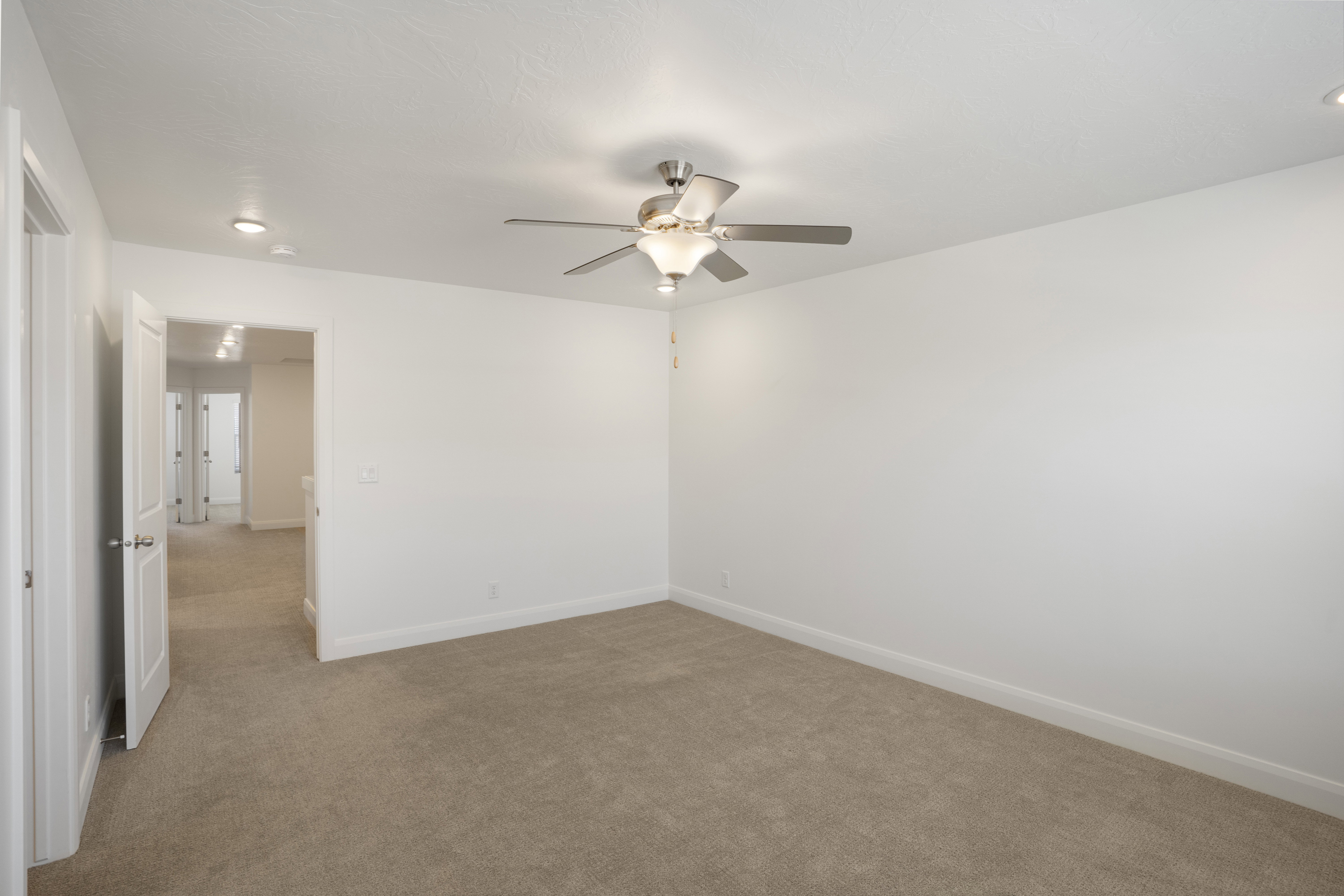 Neutral carpeted room featuring a ceiling fan with integrated lighting, recessed ceiling lights, and white baseboards