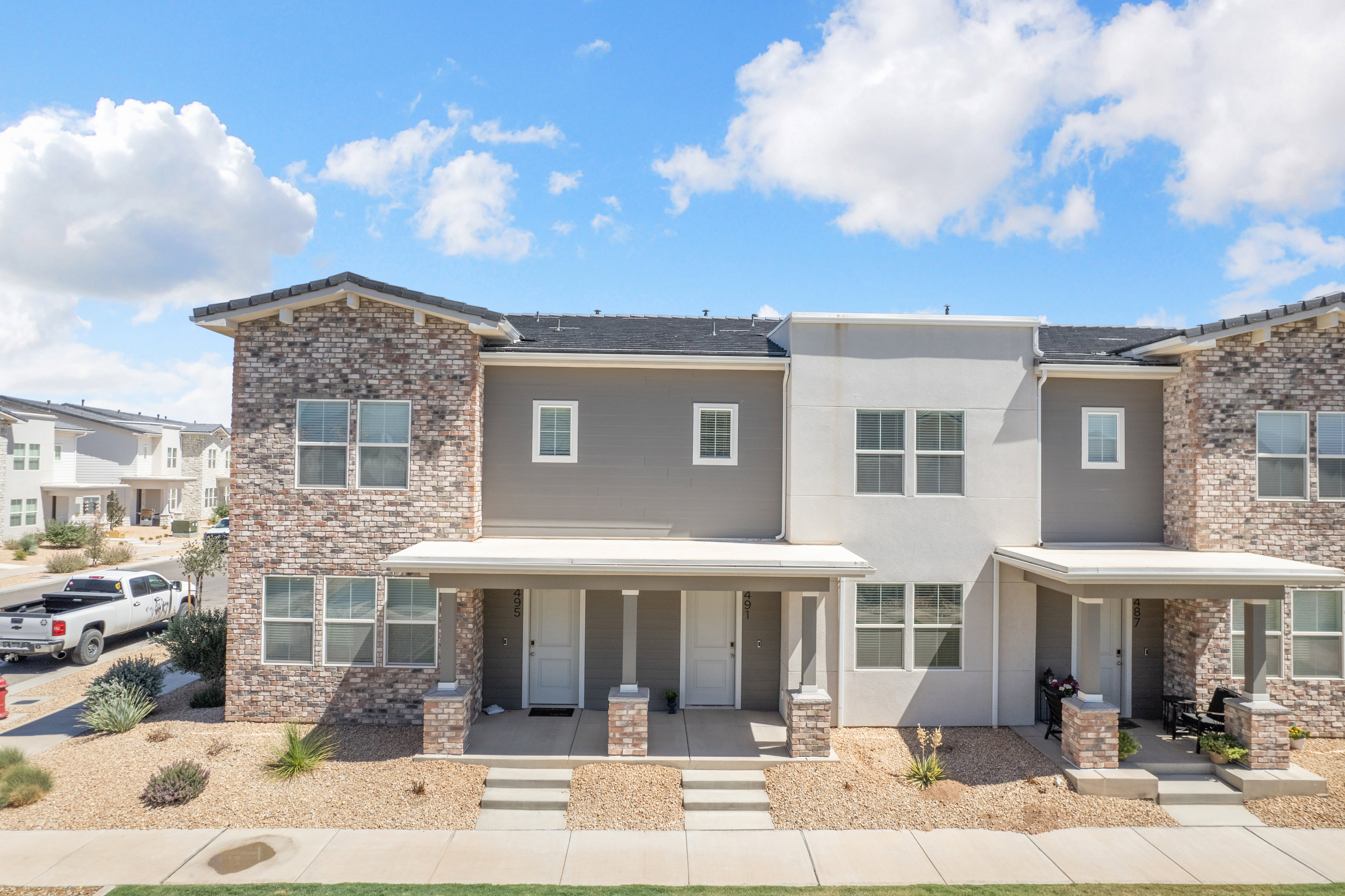 Multi-level townhome exterior featuring an architectural shingle roof and a blend of brick and stucco finishes