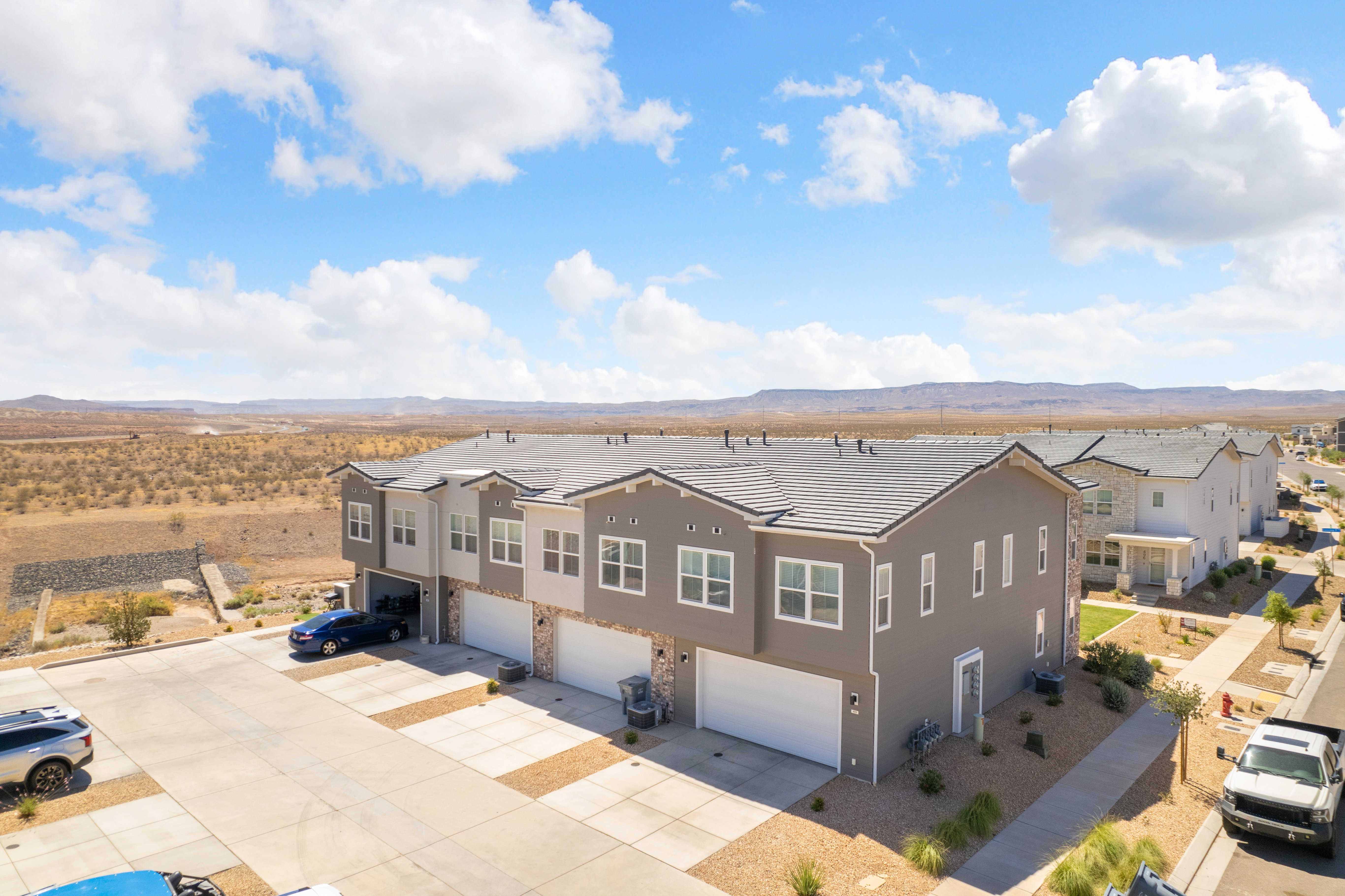 Modern townhome exterior with a multi-tone stucco and stone facade, private garage, and desert landscaping