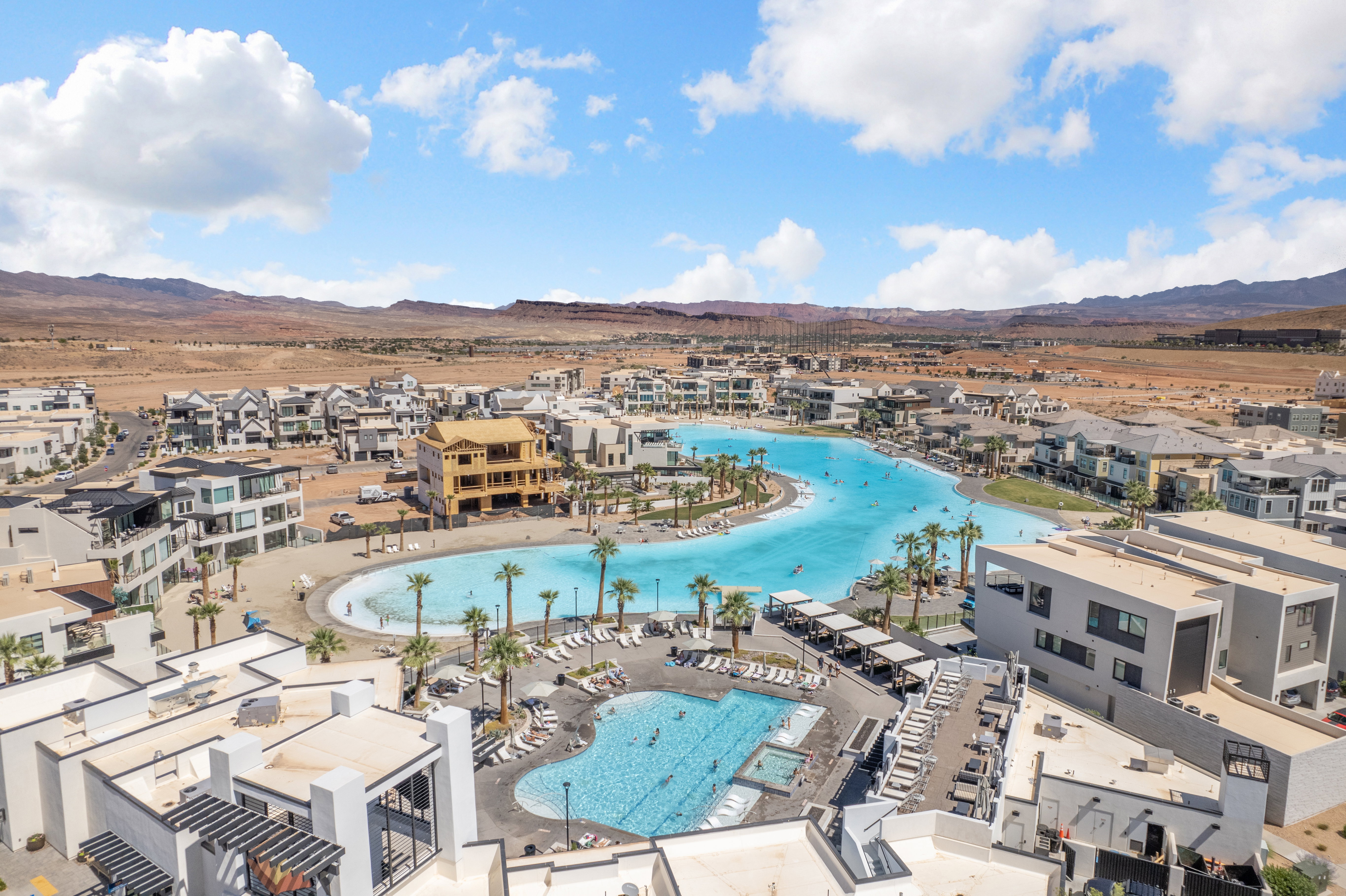 Lagoon-style pool with sandy beach entry surrounded by residential properties and mature palm trees