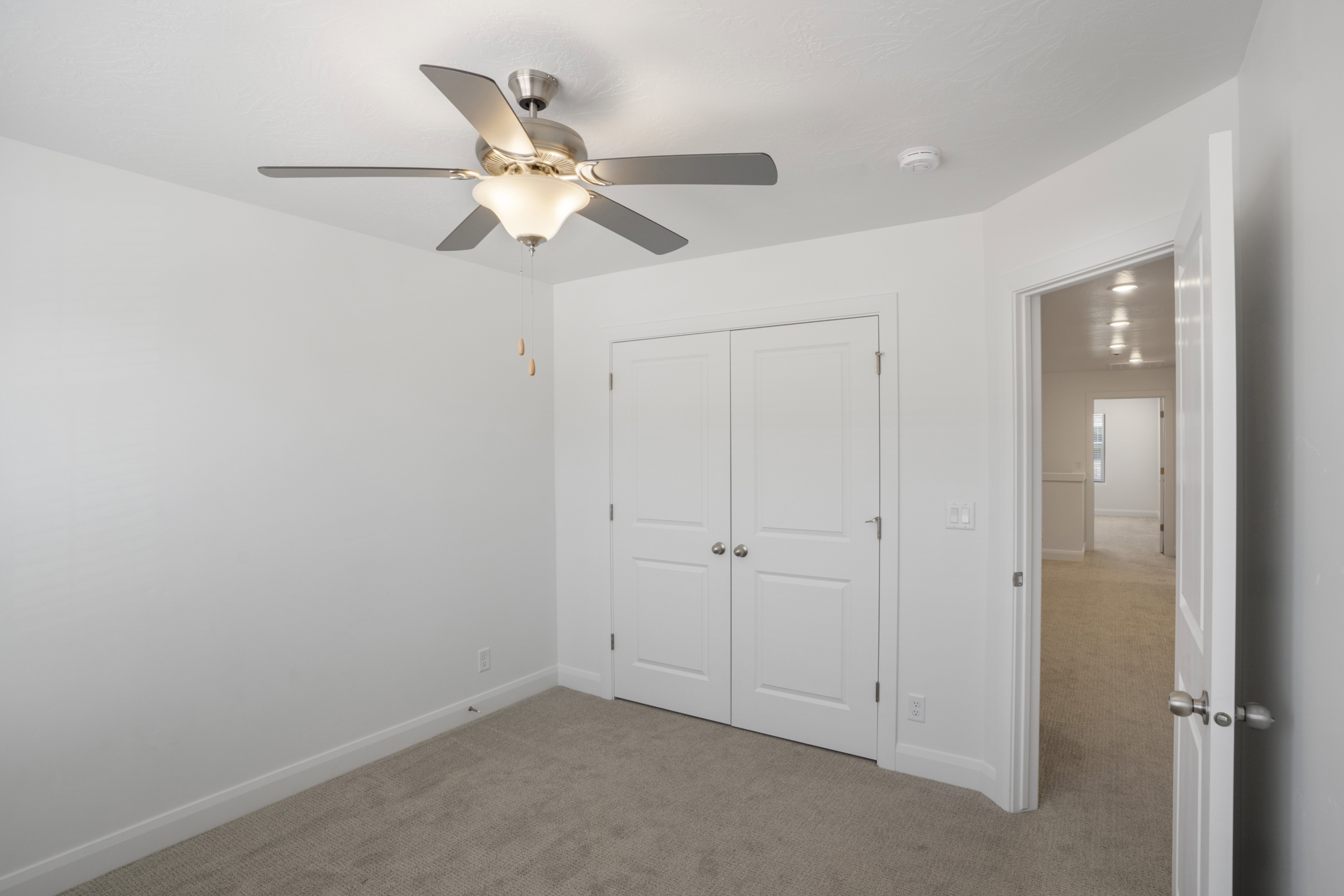 Neutral wall paint, ceiling fan with integrated lighting, bi-fold closet doors, wall-to-wall carpeting, and white trim