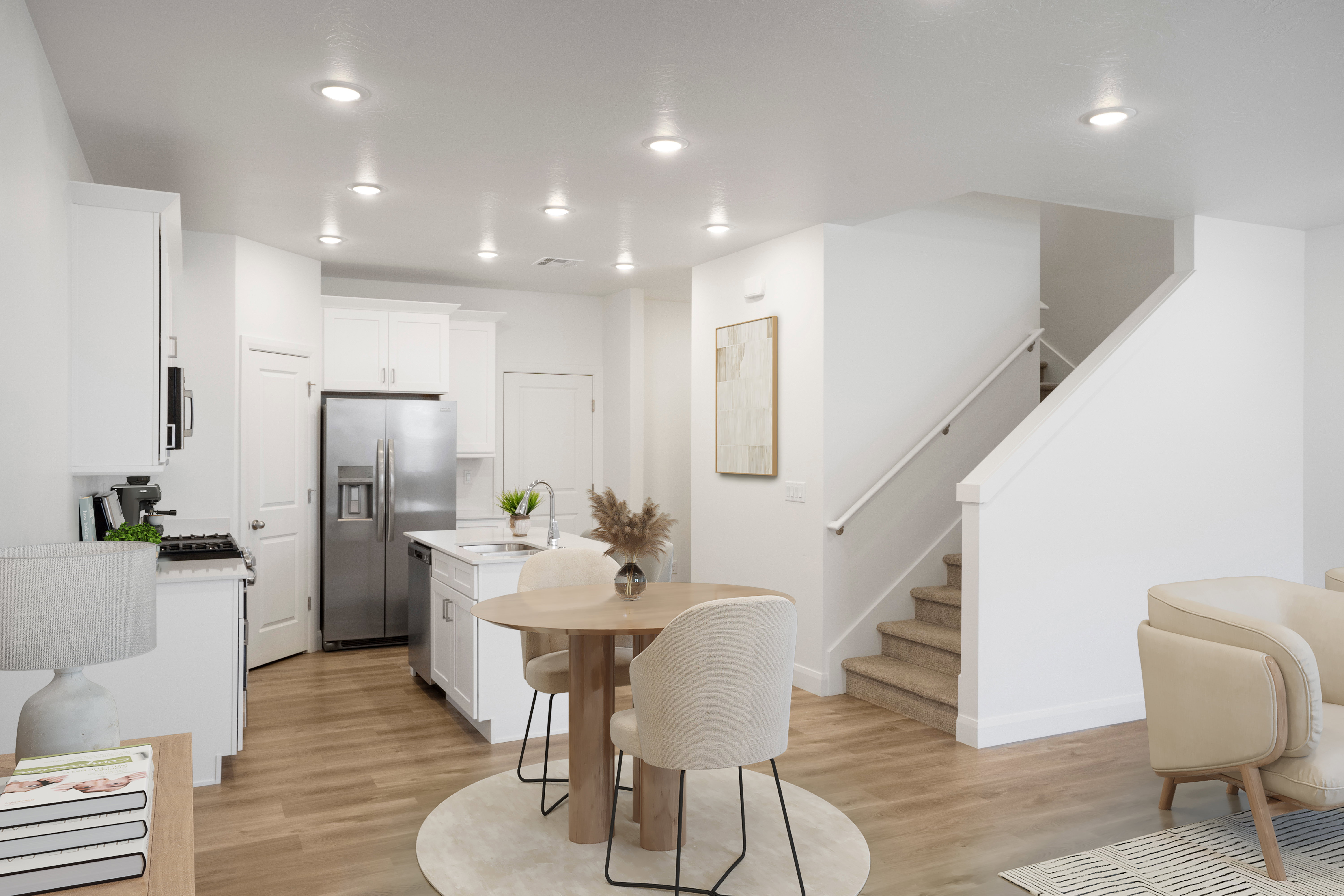 Open-concept kitchen featuring white cabinetry, stainless steel appliances, a center island with sink, and recessed lighting