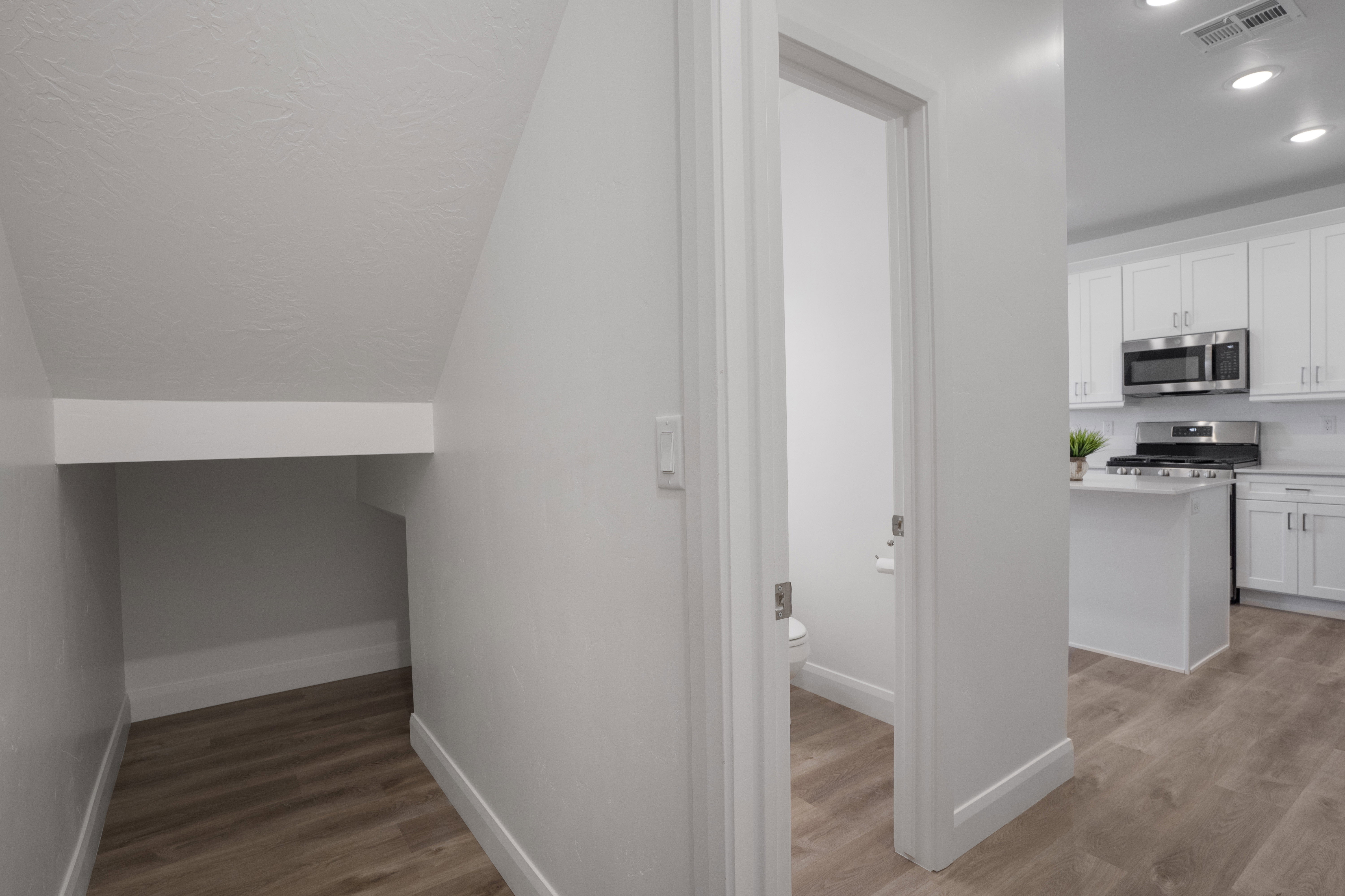 Under-stair storage area with wood-finish flooring, white baseboards, and a white wall finish