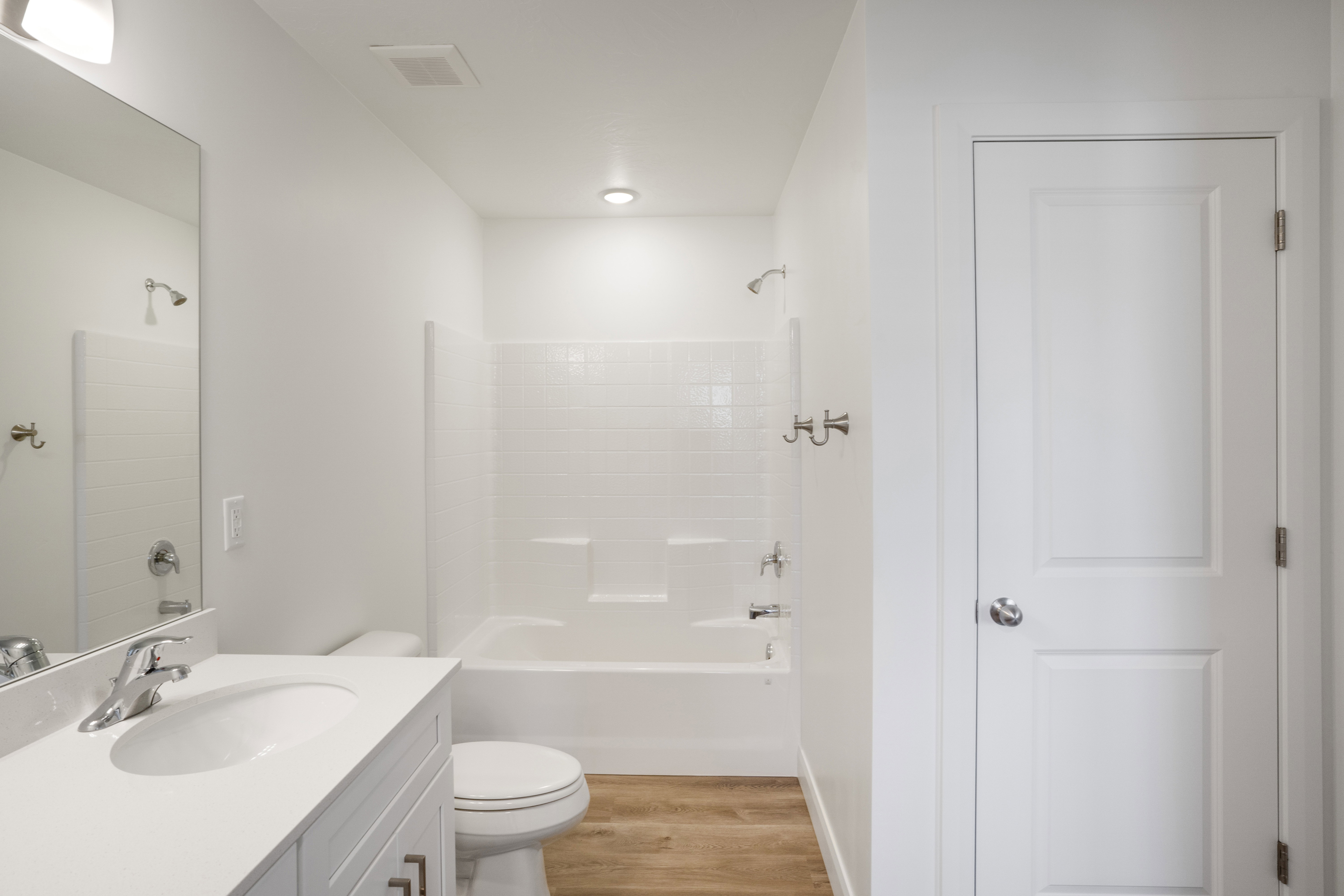 Bathroom featuring a tub/shower combination with white subway tile surround, single vanity with integrated sink and chrome faucet, recessed lighting, and wood-finish flooring
