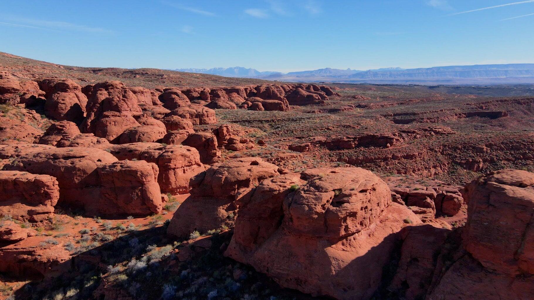 Expansive desert landscape featuring red rock formations and distant mountain ranges