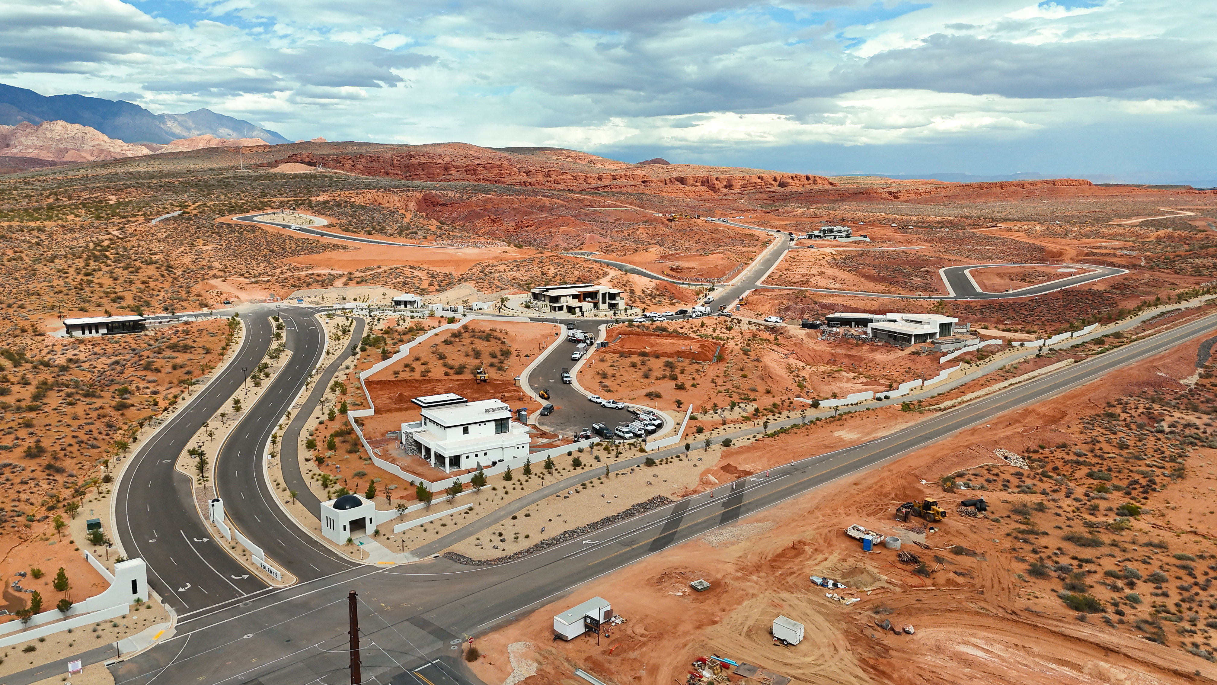 Aerial perspective showcasing a developing residential area with modern architectural homes set against a mountainous desert landscape