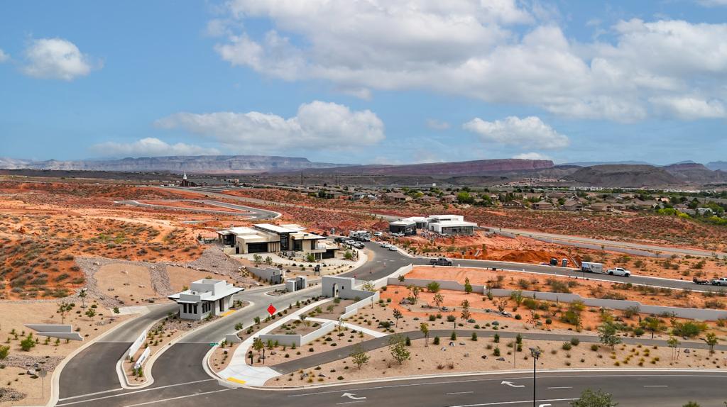 Contemporary property featuring a gated entry, paved roads, desert landscaping, and distant mountain backdrops