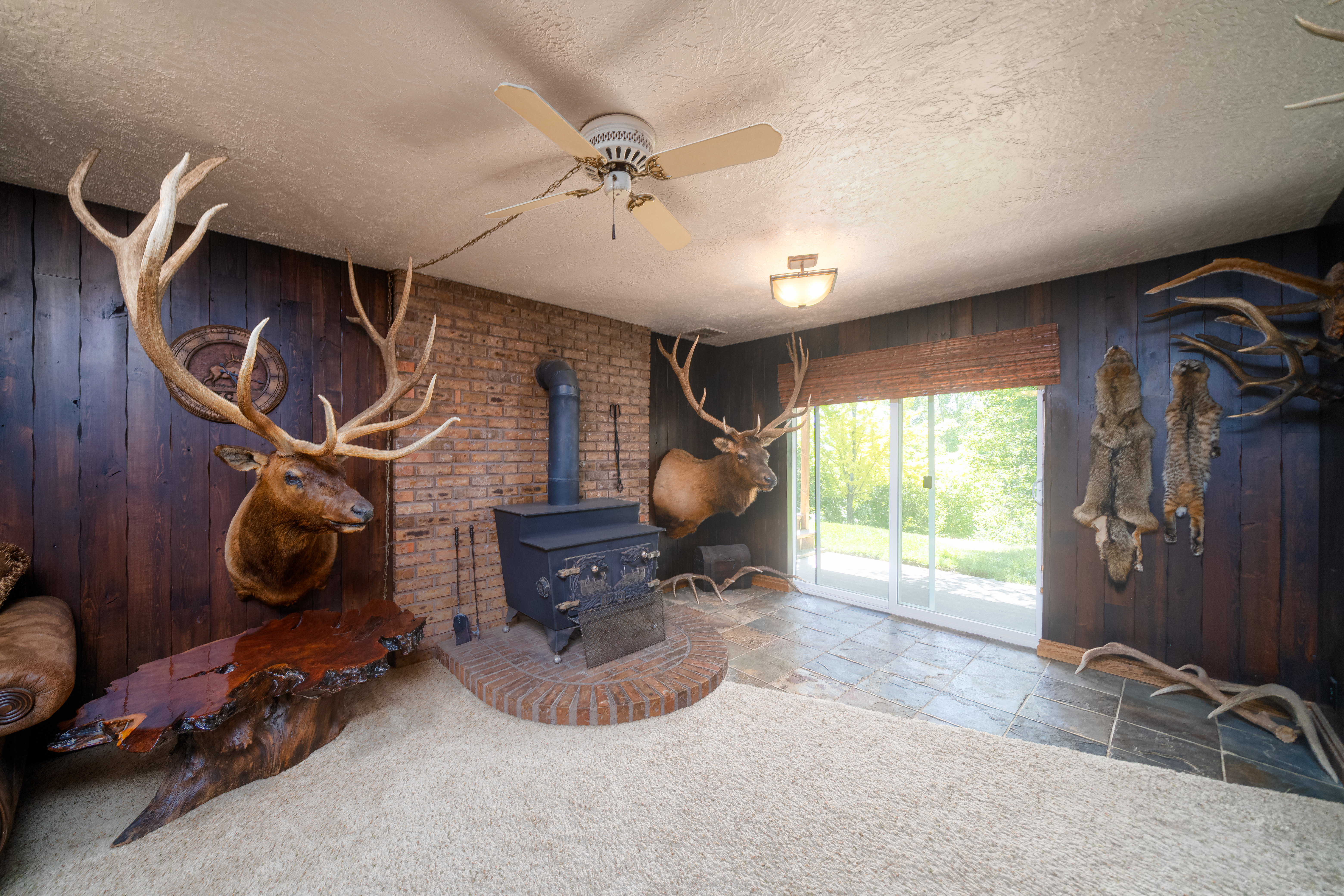 Wood-paneled room featuring a brick accent wall with a wood-burning stove and hearth