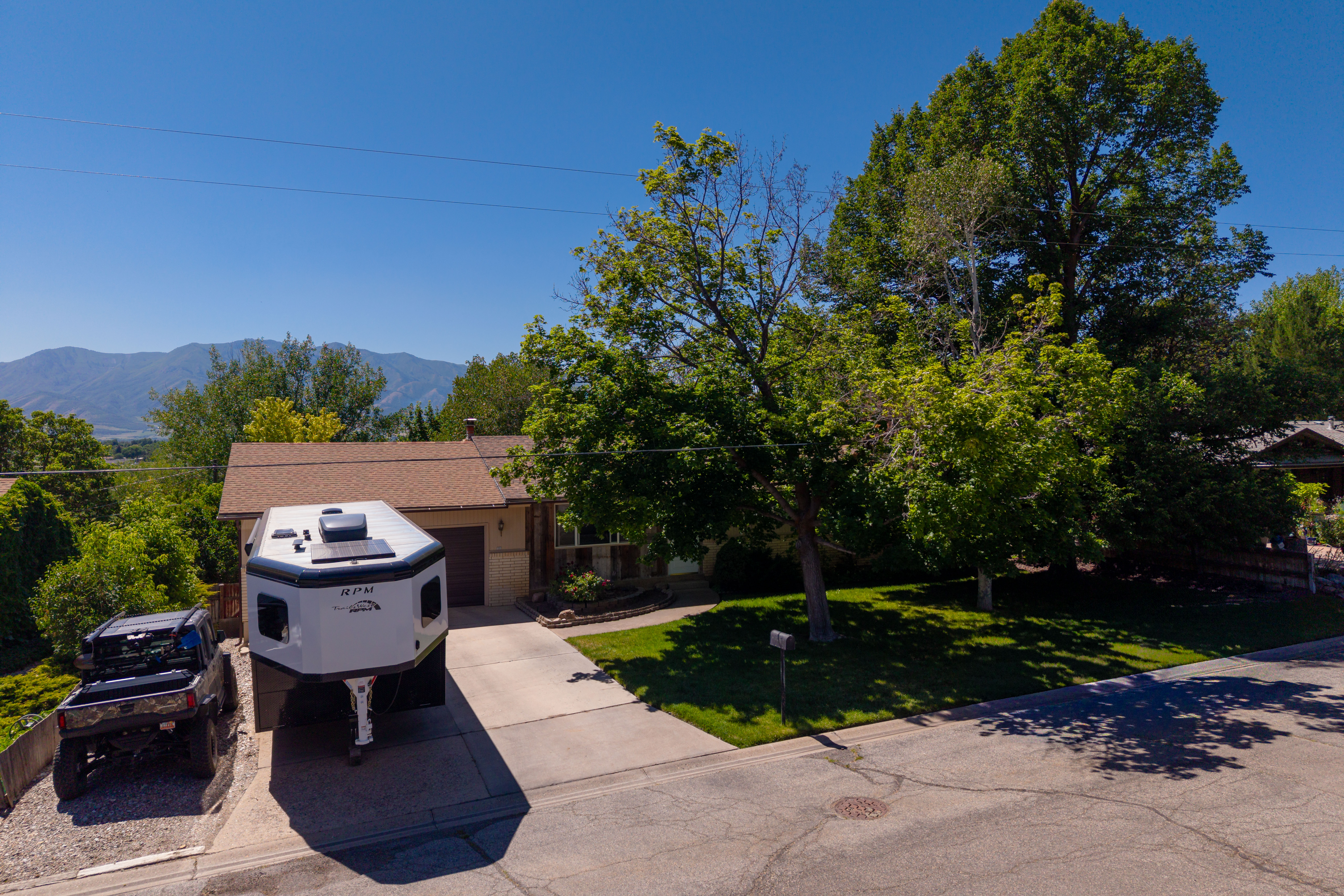 Ranch-style residence featuring a prominent garage, a concrete driveway, and a gravel parking area