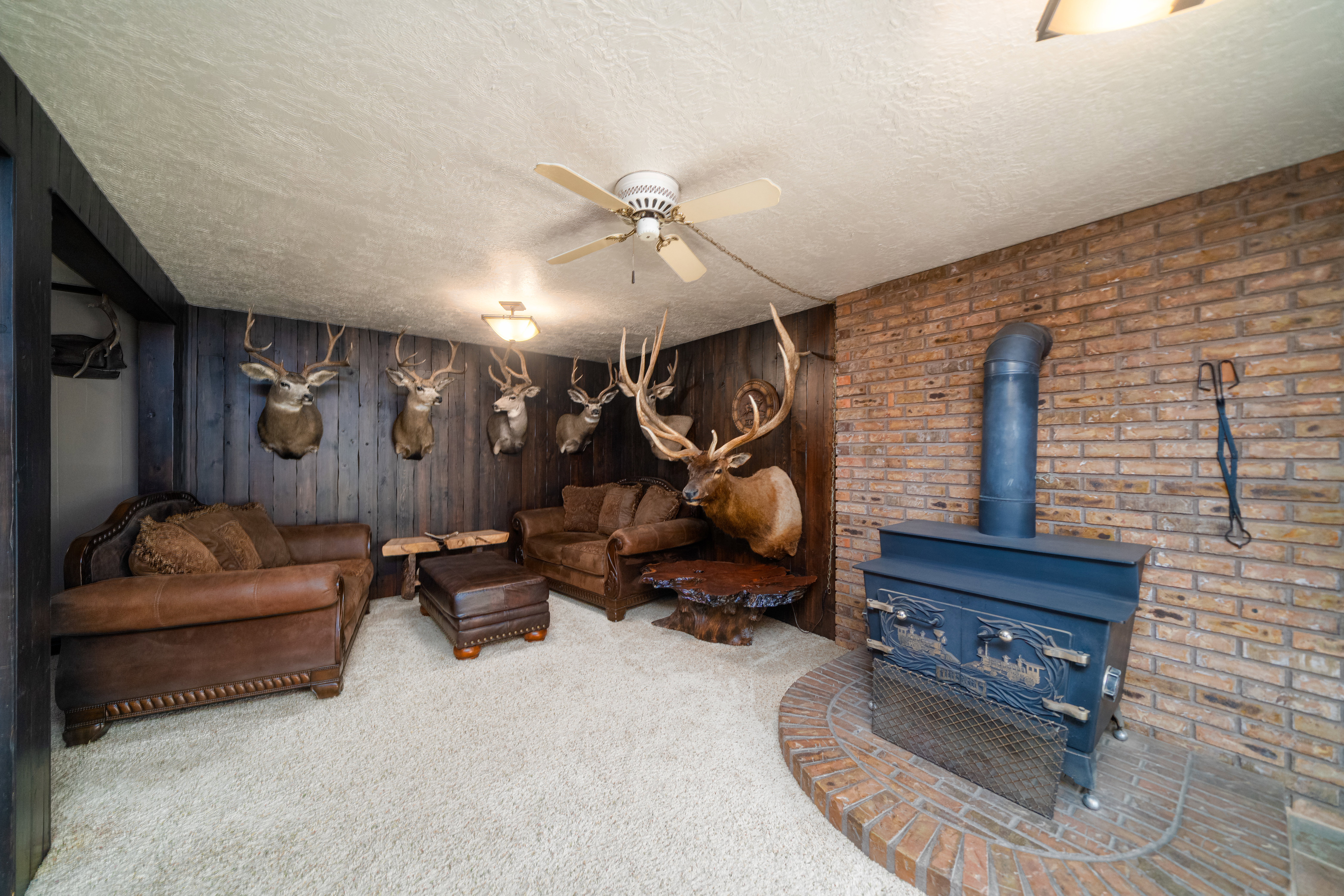 Living space featuring a brick accent wall, wood-paneled walls, and soft carpet flooring