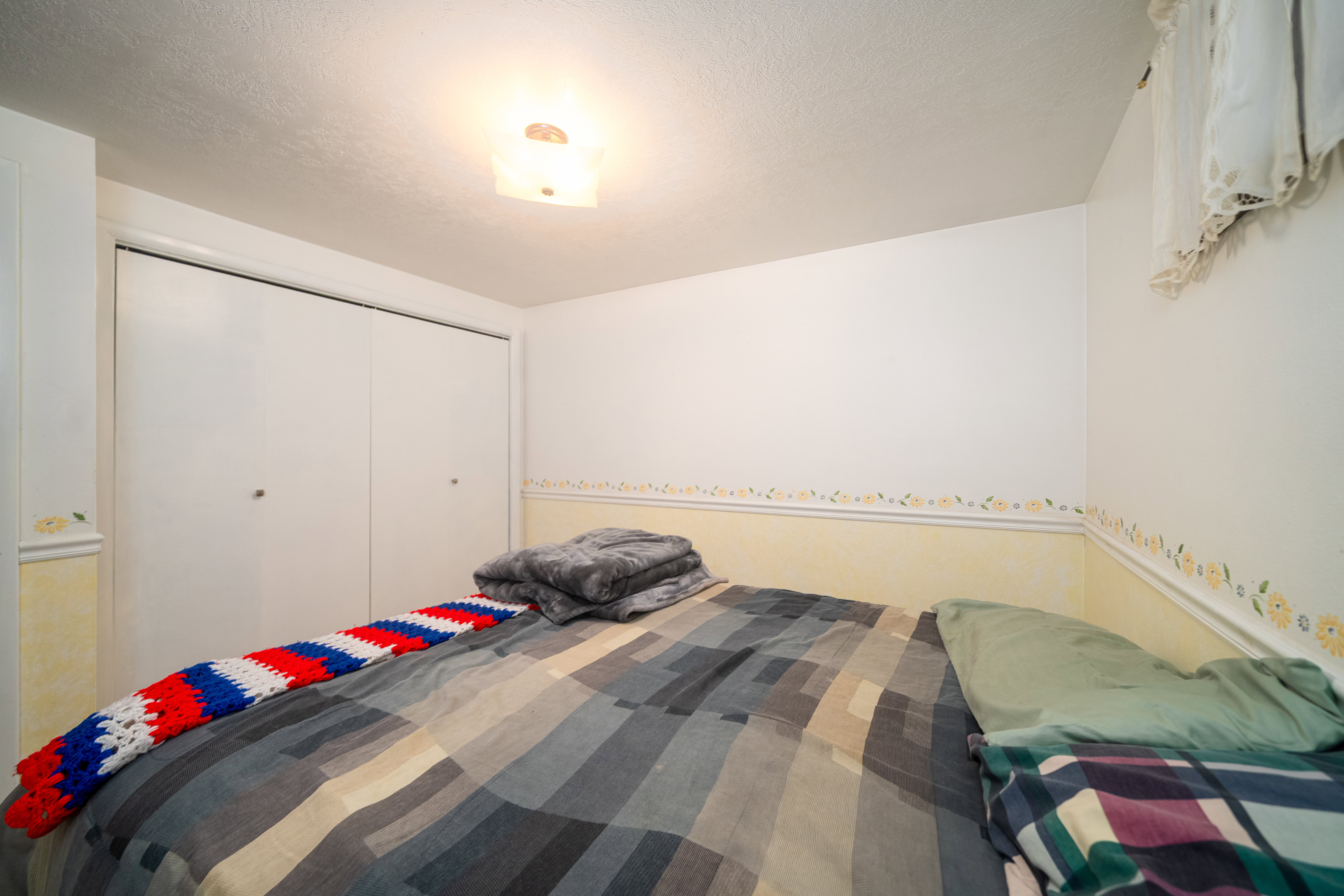 Room featuring bi-fold closet doors, wall-mounted ceiling light fixture, and painted walls