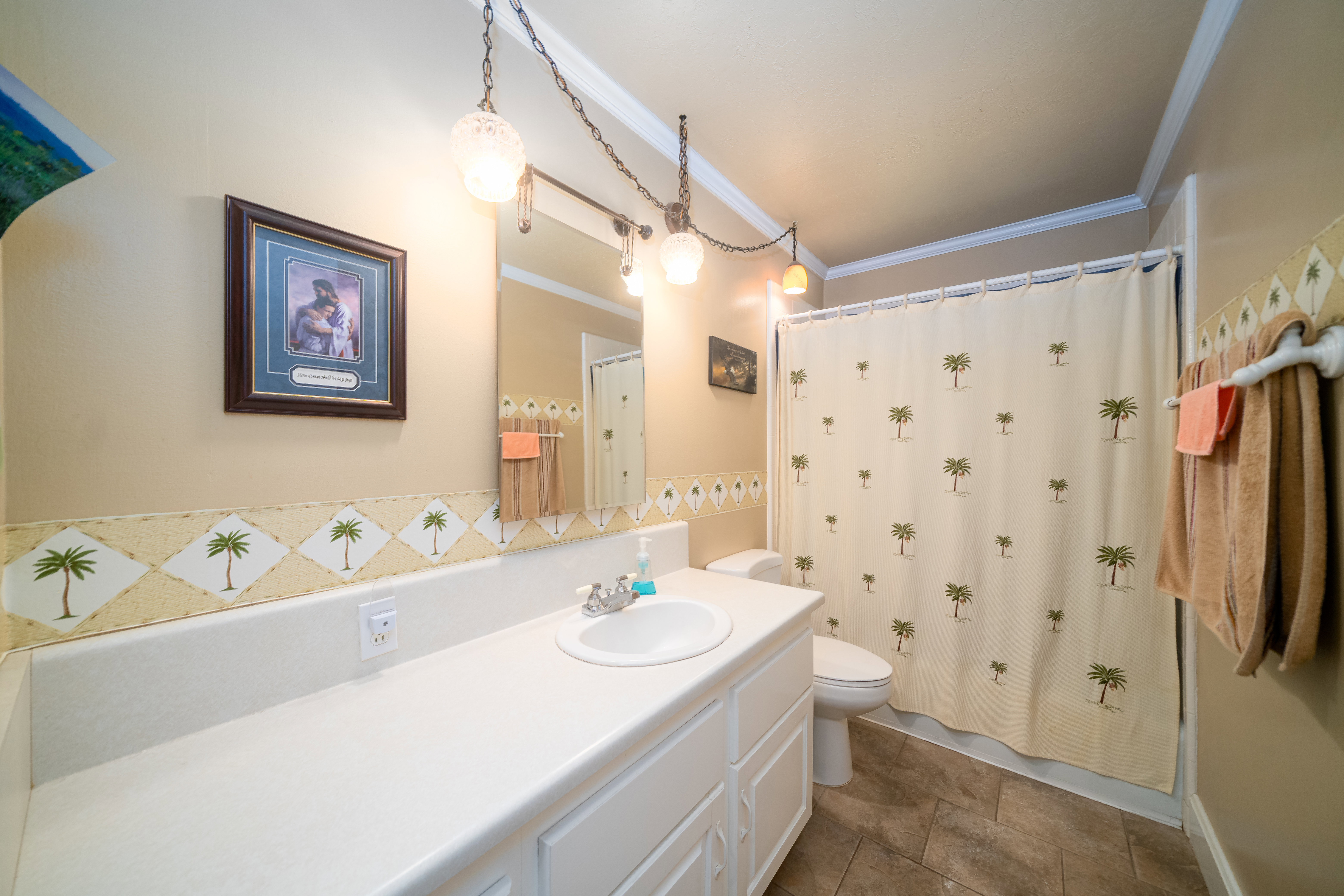 Bathroom featuring a white vanity with integrated sink, a large wall mirror, and pendant lighting fixtures