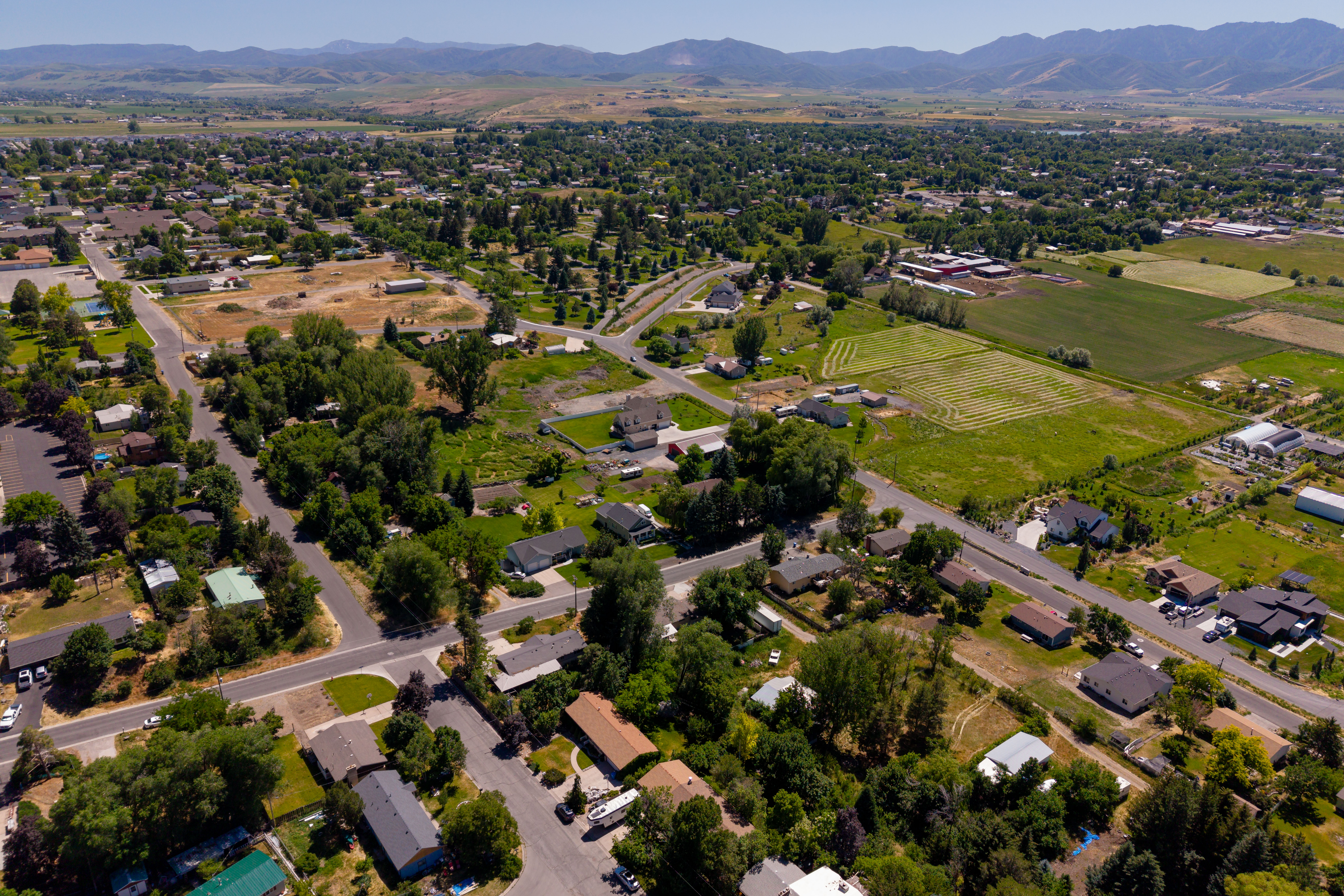Expansive aerial perspective showcasing a residential community with abundant mature trees and mountainous terrain in the background